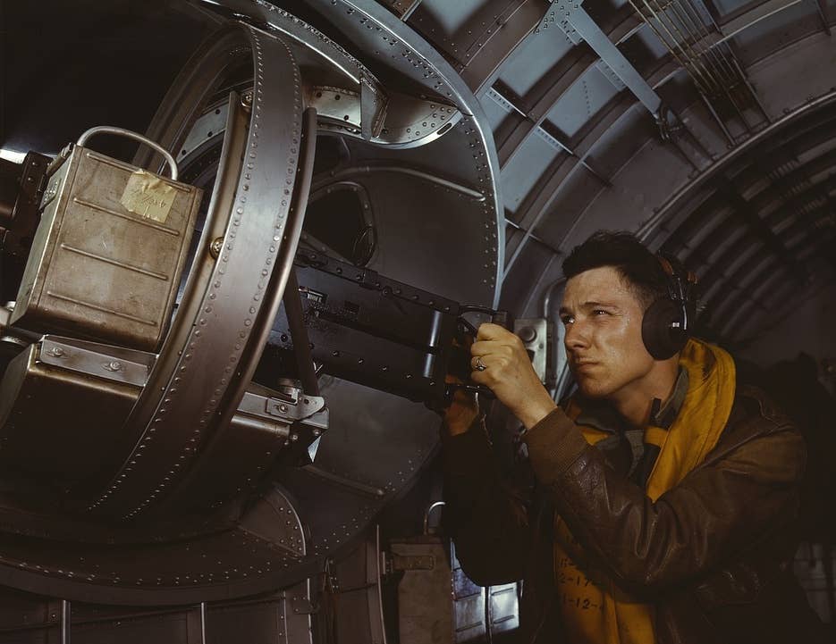 “Hitler would like this man to go home and forget about the war. A good American non-com at the side machine gun of a huge B-17 bomber is a man who knows his business and works hard at it” — the original caption of a staged wartime propaganda photo showing a B-17 waist gunner. <em>Collection Library of Congress, Transfer from U.S. Office of War Information, 1944</em>