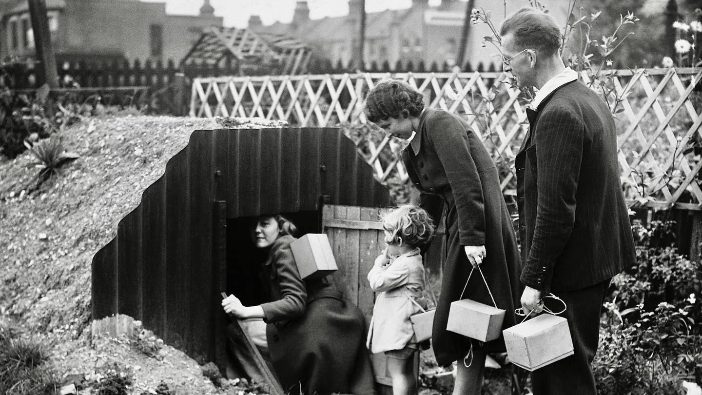 A family, each carrying their gas masks in a little box, enter the dug-out air raid shelter in their garden, 1939. (Photo by © Hulton-Deutsch Collection/CORBIS/Corbis via Getty Images)