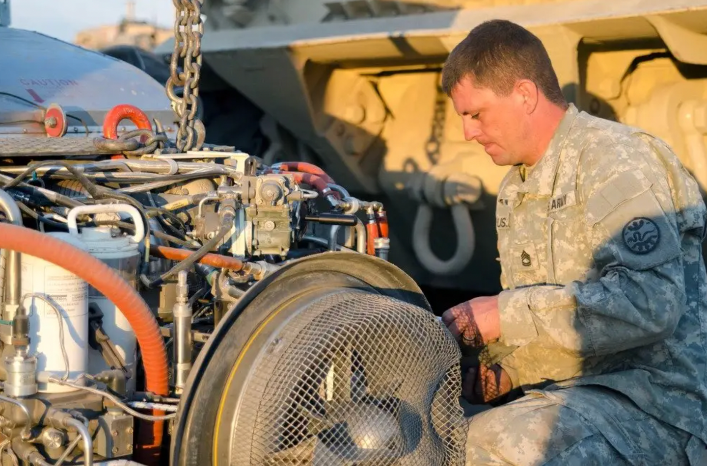 A U.S. Army tank mechanic works on the engine of an Abrams M1A2 System Enhanced Package (SEP) tank. <em>U.S. Army photo by 1st Sgt. Kevin Hartman, 115 Mobile Public Affairs Detachment, Oregon Army National Guard</em>
