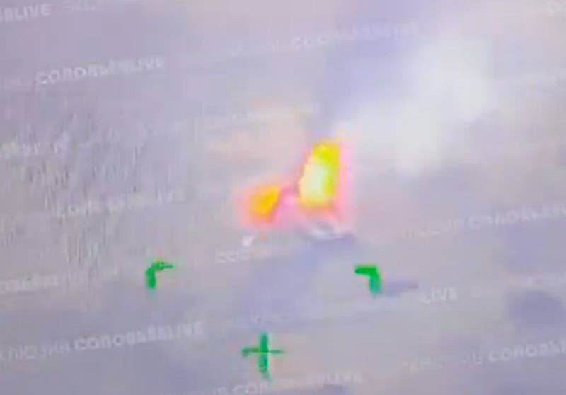 A still frame from a very low-quality video claiming to show the Ukrainian Abrams tank on fire after being attacked, with a large fire seen blazing upward. <em>screen capture via X</em>