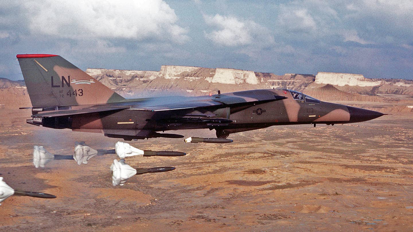 An air-to-air right side view of a 494th Tactical Fighter Squadron, 48th Tactical Fighter Wing F-111F aircraft releasing its load of Mark 82 high-drag bombs over the Bardenas Reales range. The 494th TFS has been deployed to Zaragoza Air Base for training.