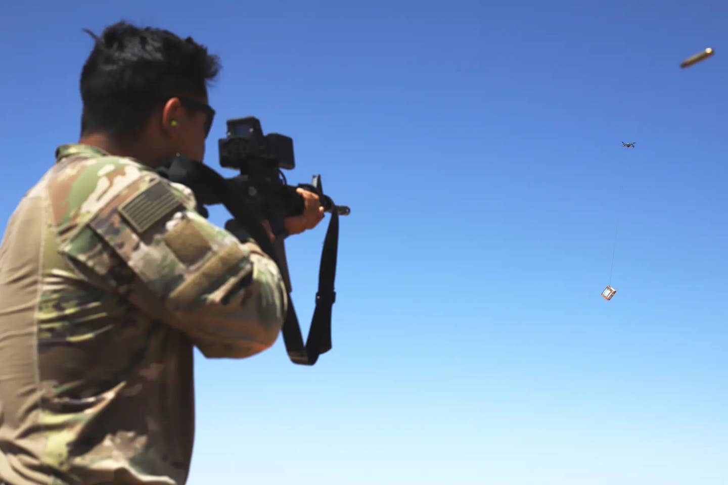 A member of the U.S. Army fires an M4 carbine with a SMASH 2000 sight at a box suspended underneath a small drone during training in Syria in 2020. <em>U.S. Army</em>