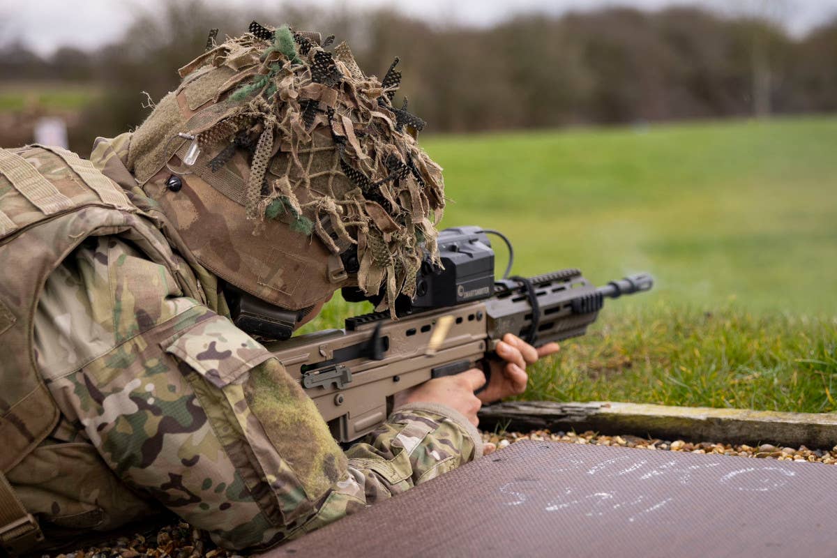 A member of the 16th Air Assault Brigade Combat Team wears a helmet with camouflage webbing while training with an L85A3 rifle with a SMASH X4 sight. <em>Crown Copyright</em>