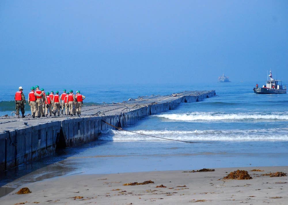 Midshipmen walk along the Joint Logistics Over-The-Shore Admin Pier, an 800-foot long, small-craft pier, created by attaching nine non-powered Navy lighterage causeway sections together. JLOTS 2008 is an engineering, logistical training exercise between Army and Navy units.&nbsp;(U.S. Navy)