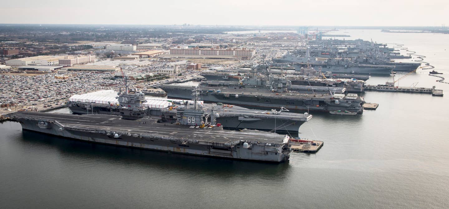 A shot taken in 2012 showing the long pier at Naval Base Norfolk packed with carriers and amphibious assault ships. <em>USN</em>