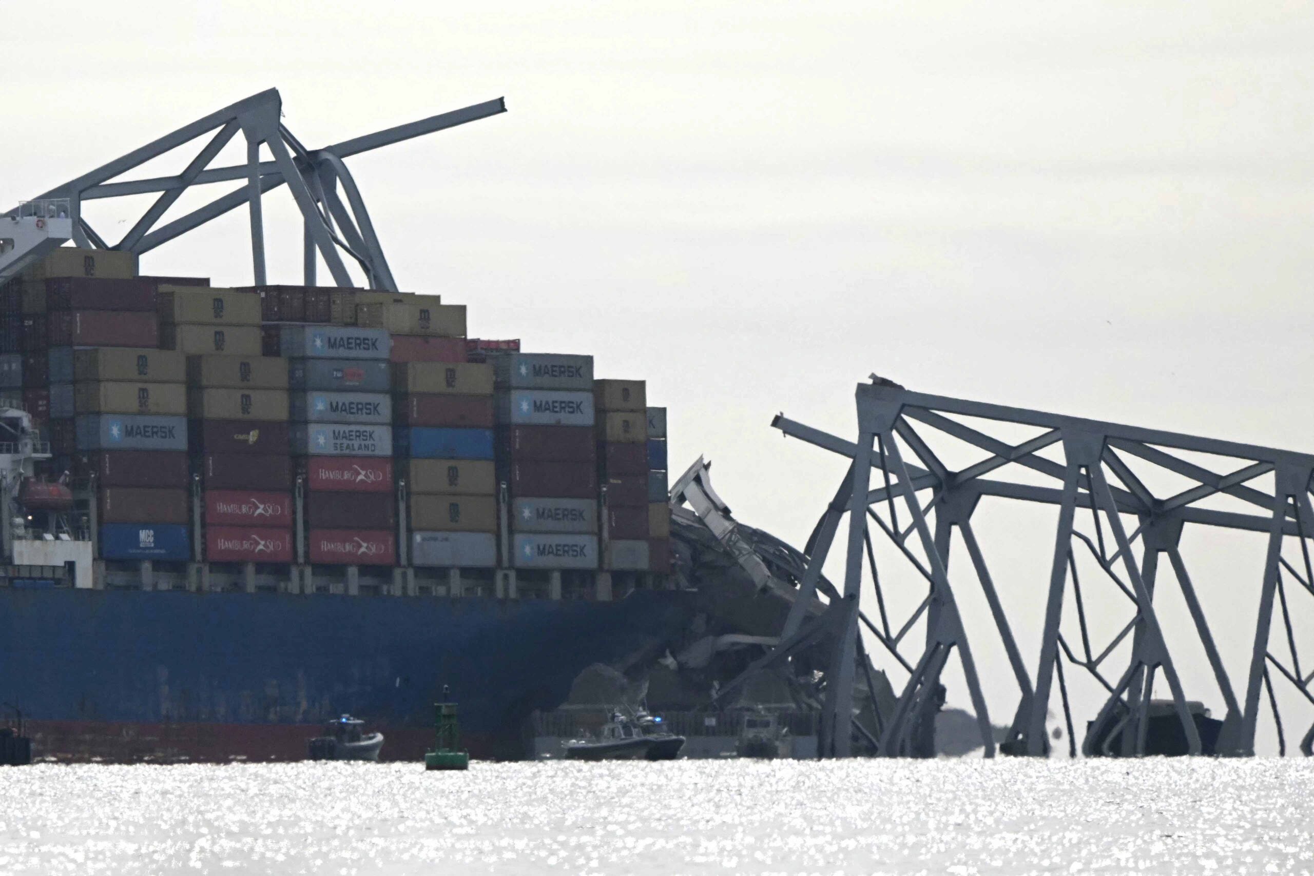 The steel frame of the Francis Scott Key Bridge sits on top of the container ship Dali after the bridge collapsed, Baltimore, Maryland, on March 26, 2024. The bridge collapsed early March 26 after being struck by the Singapore-flagged Dali, sending multiple vehicles and people plunging into the frigid harbor below. There was no immediate confirmation of the cause of the disaster, but Baltimore's Police Commissioner Richard Worley said there was "no indication" of terrorism. (Photo by Mandel NGAN / AFP)