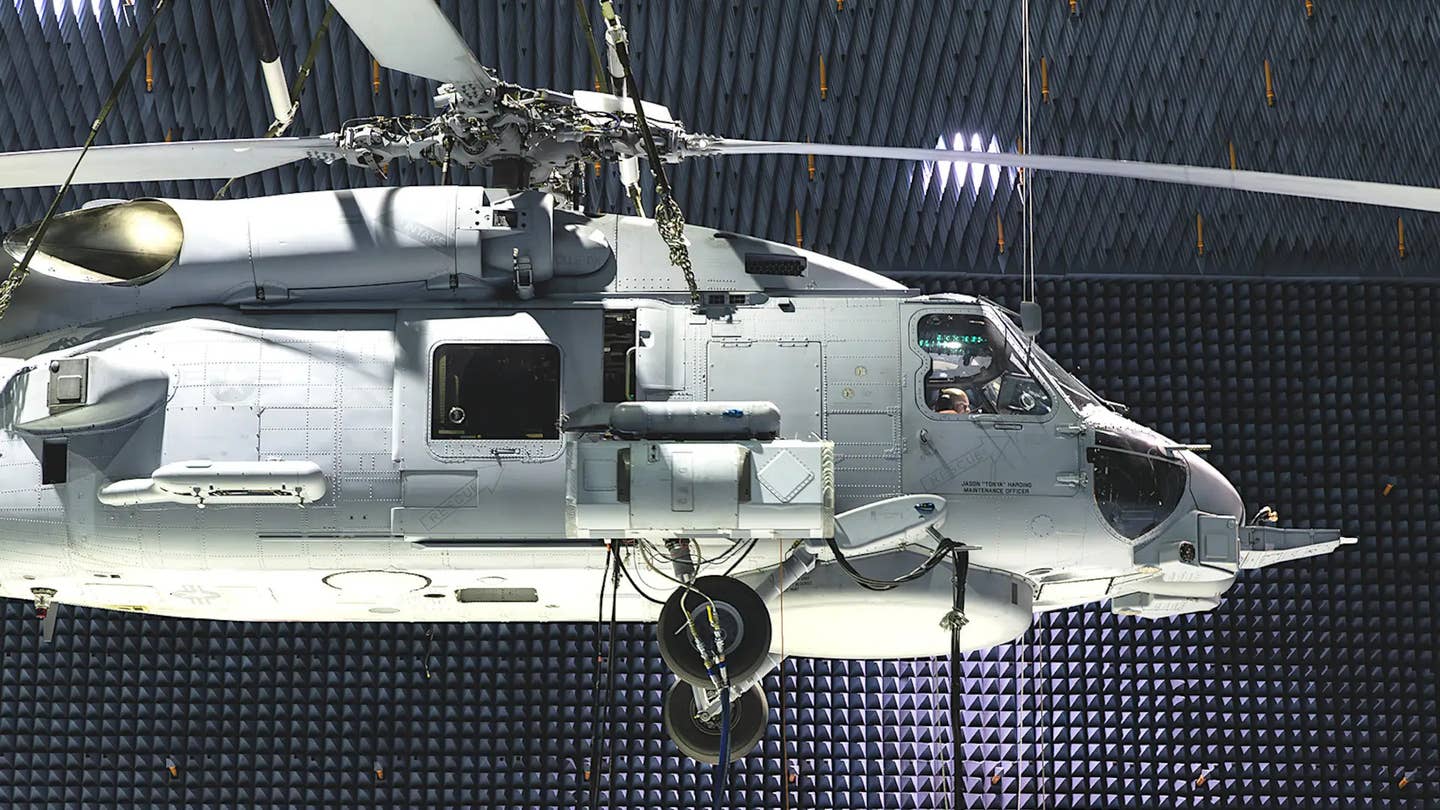 An MH-60R with an AN/ALQ-248 Advanced Off-Board Electronic Warfare system pod loaded onto its right forward stub wing suspended in the anechoic test chamber at Naval Air Station Patuxent River. <em>USN via Lockheed Martin</em>
