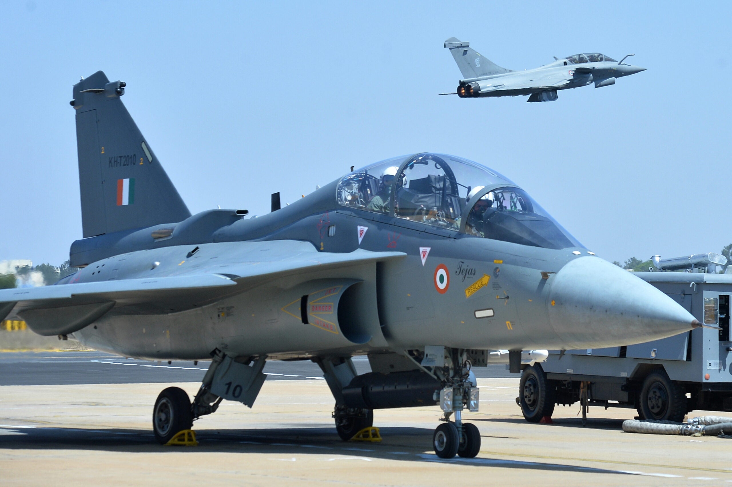 A French Rafale fighter flies over an Indian Airforce Tejas Aircraft with Bipin Rawat, the 27th Chief of Army Staff of the Indian Army on board in the co-pilot seat before take off during the Aero India airshow at the Yelahanka Air Force station, in Bangalore on February 21, 2019. - The Aero India 2019 airshow starts on February 20 and ends on February 24. (Photo by MANJUNATH KIRAN / AFP)        (Photo credit should read MANJUNATH KIRAN/AFP via Getty Images)