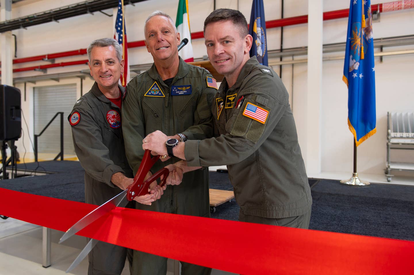 From left to right, VUP-19 commander Capt. Ronald H. Rumfelt, Jr., head of Naval Air Forces Vice Adm. Daniel “Undra” Cheever, Commander, and commander of NAS Sigonella Capt. Aaron Shoemaker cut a ceremonial ribbon in a new hangar at the base in Italy dedicated to supporting MQ-4C operations during a ceremony on March 2, 2024. <em>USN</em>