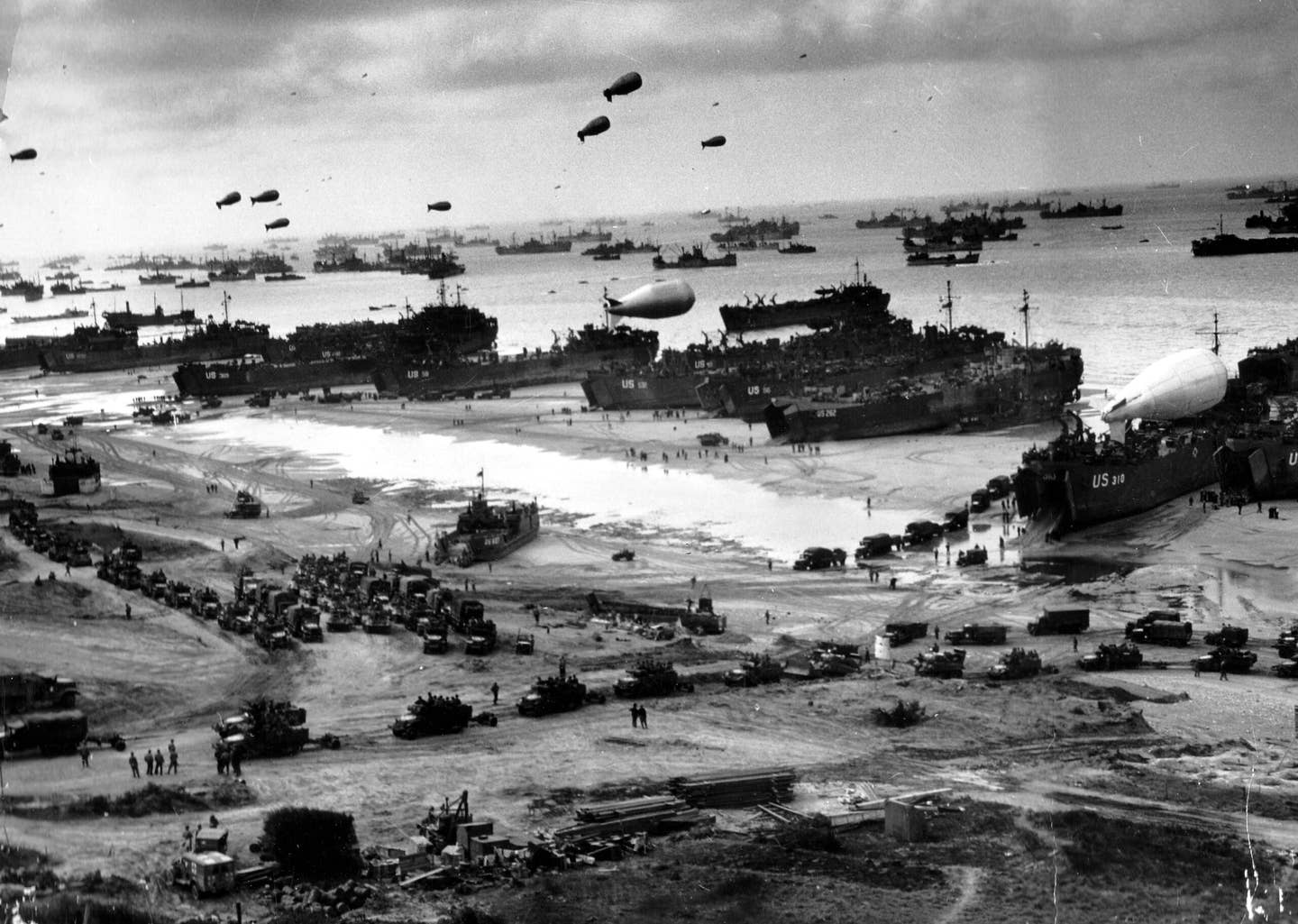 Landing craft and ships unload troops and supplies at Omaha Beach a few days after D-Day. <em>Conseil Régional de Basse-Normandie/U.S. National Archives</em>
