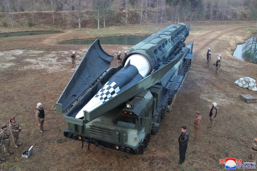 A picture of the newly unveiled Hwasongpho-16B on its TEL, with the clamshell at the front open. North Korean leader Kim Jong Un, wearing a black leather jacket, is seen to the right.<em> KCNA</em>