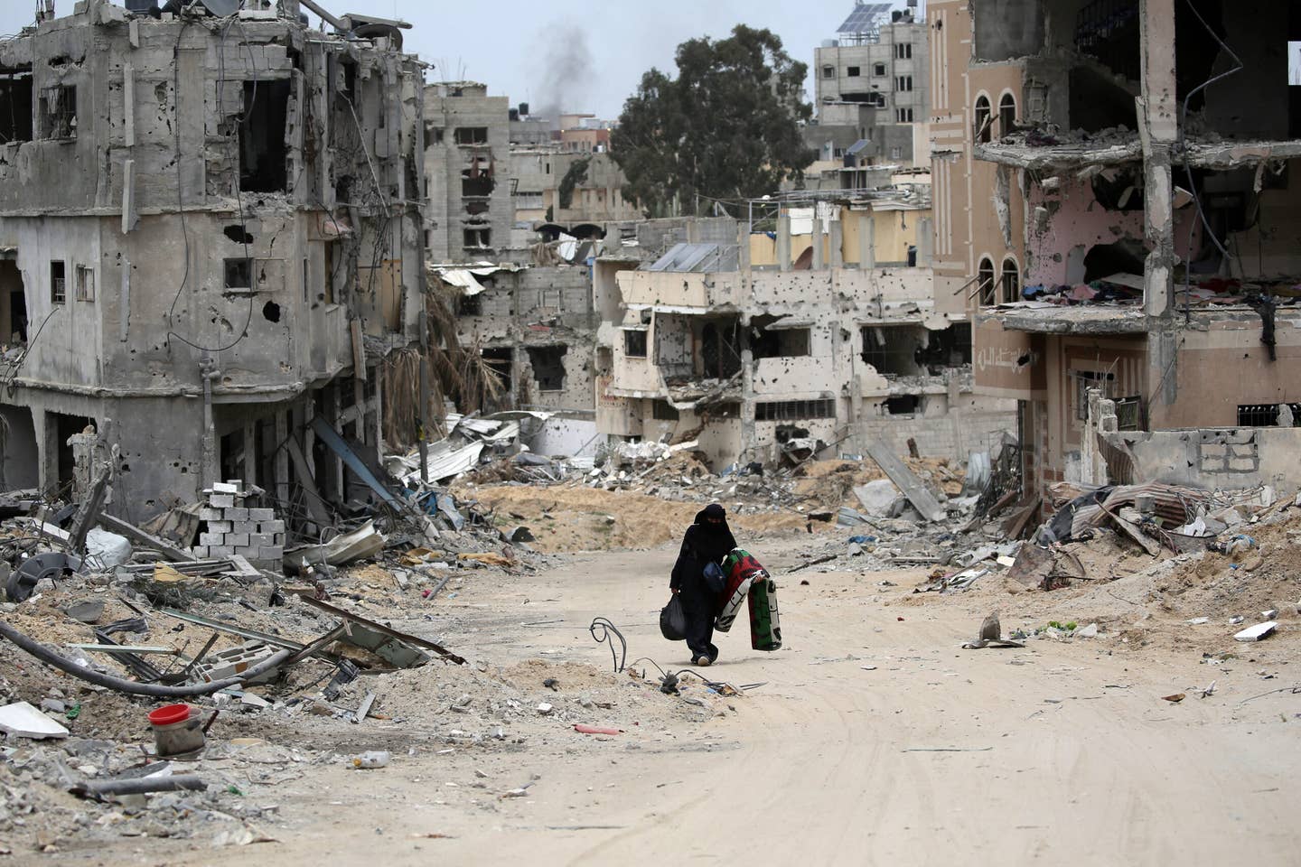 A Palestinian woman carrying some belongings walks in a neighborhood devastated by Israeli bombing in Khan Yunis in the southern Gaza Strip on April 25, 2024, amid the ongoing conflict between Israel and Hamas. (Photo by -/AFP via Getty Images)