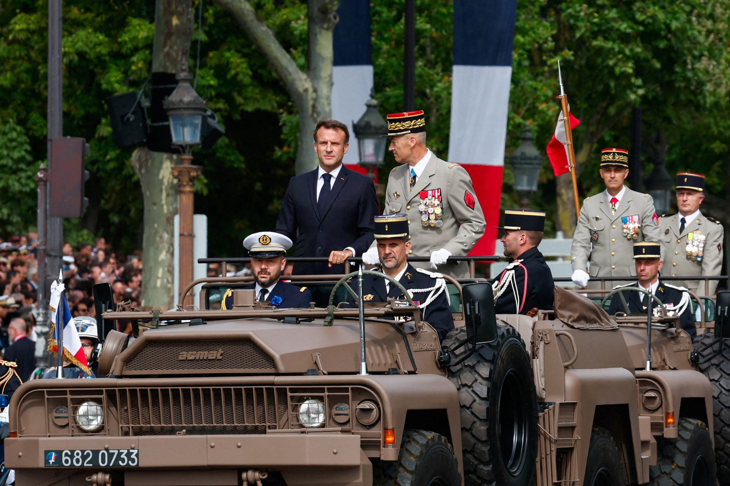French President Emmanuel Macron (center left) and Chief of the Defence Staff Thierry Burkhard stand in the command car during the Bastille Day military parade on the Champs-Élysées avenue in Paris on July 14, 2023. <em>Photo by GONZALO FUENTES/POOL/AFP via Getty Images</em>