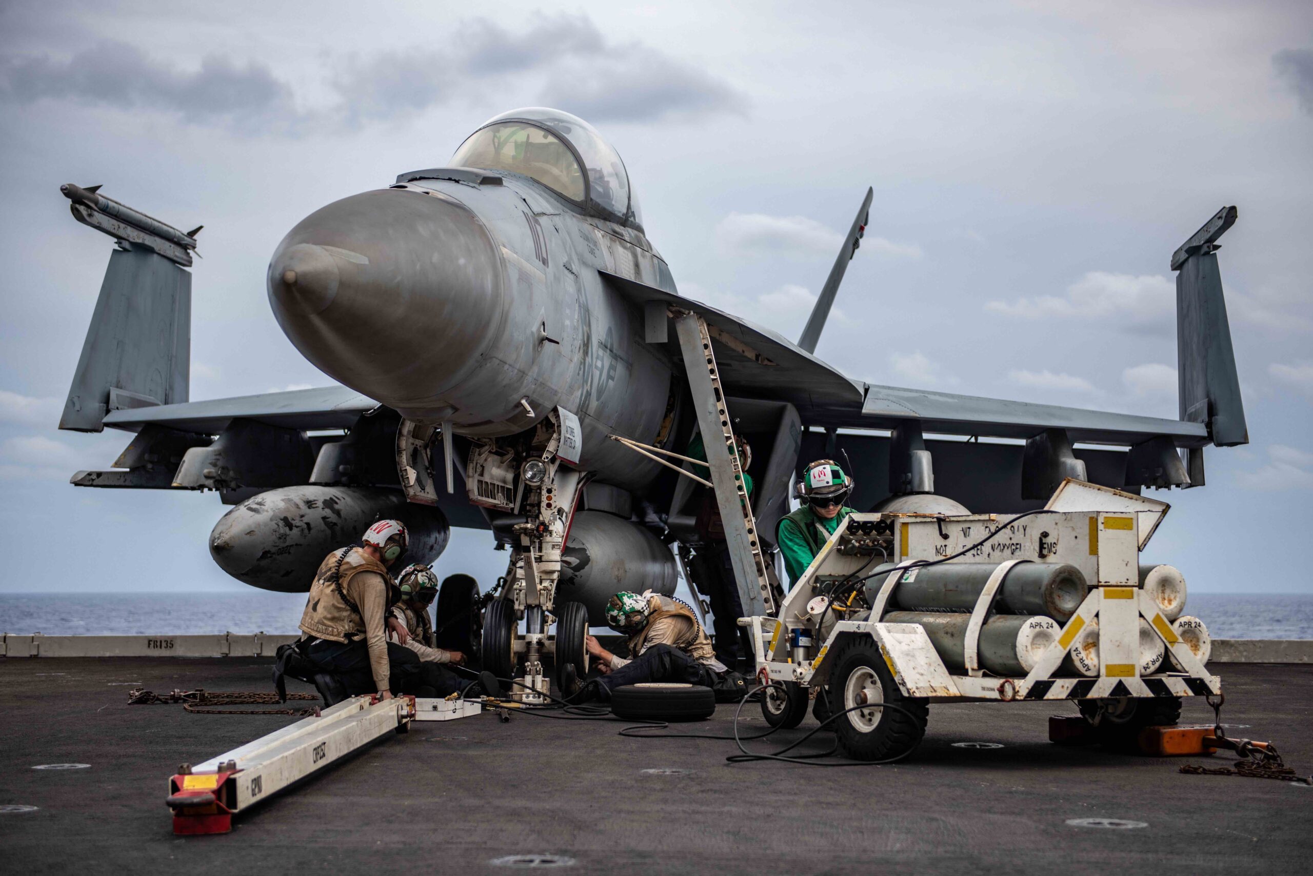 Sailors pump air into the tires of an F/A-18F Super Hornet on the flight deck of USS <em>Ronald Reagan</em>, Philippine Sea, November 11, 2023. <em>U.S. Navy Photo by Mass Communication Specialist 2nd Class Caroline H. Lui</em>