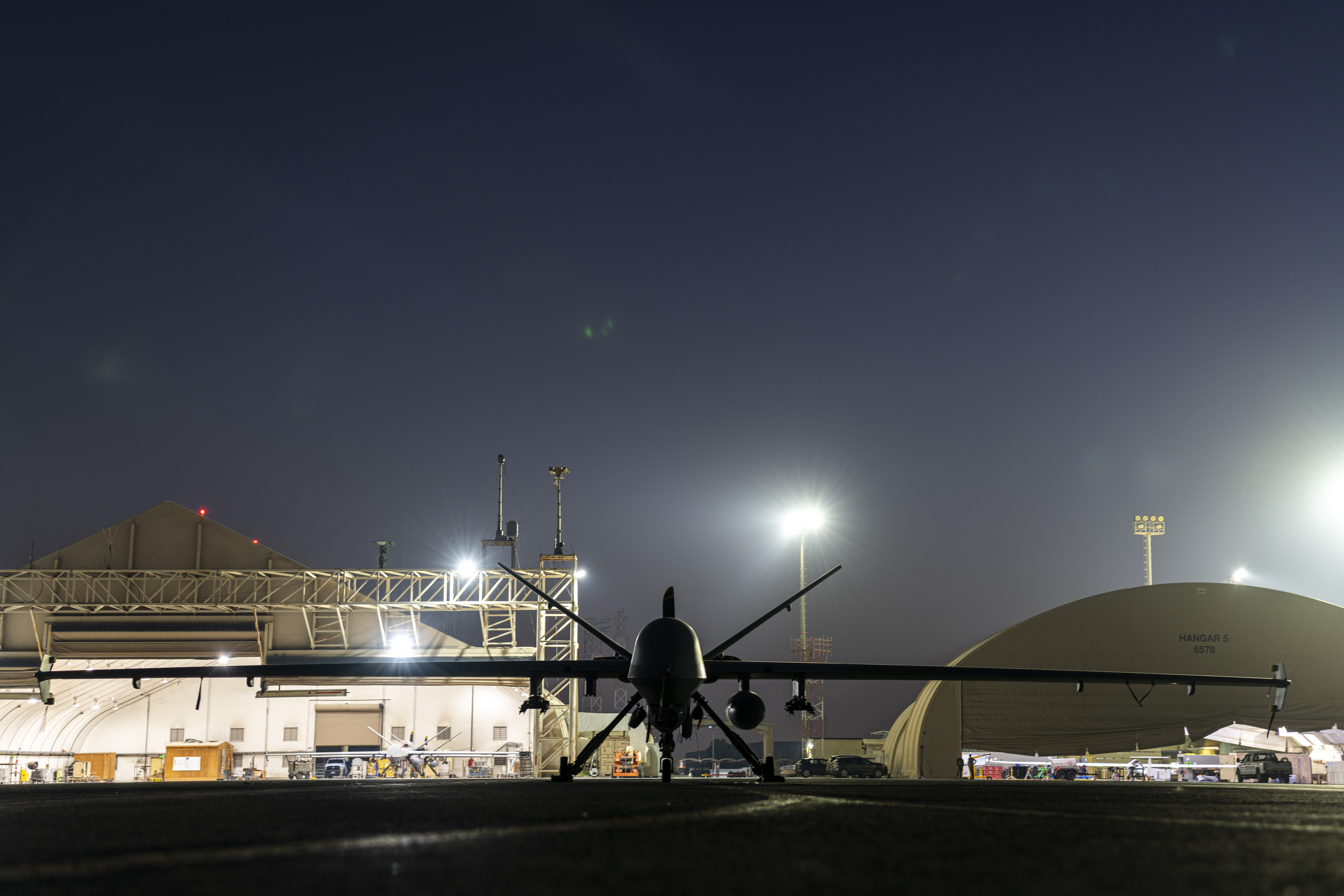 A U.S. Air Force MQ-9 Reaper, assigned within the U.S. Central Command area of responsibility, sits on the flightline before a morning flight at an undisclosed location within the U.S. Central Command area of responsibility, May 7, 2024. The ULTRA drone can be seen in the background on the right. <em>U.S. Air Force</em>