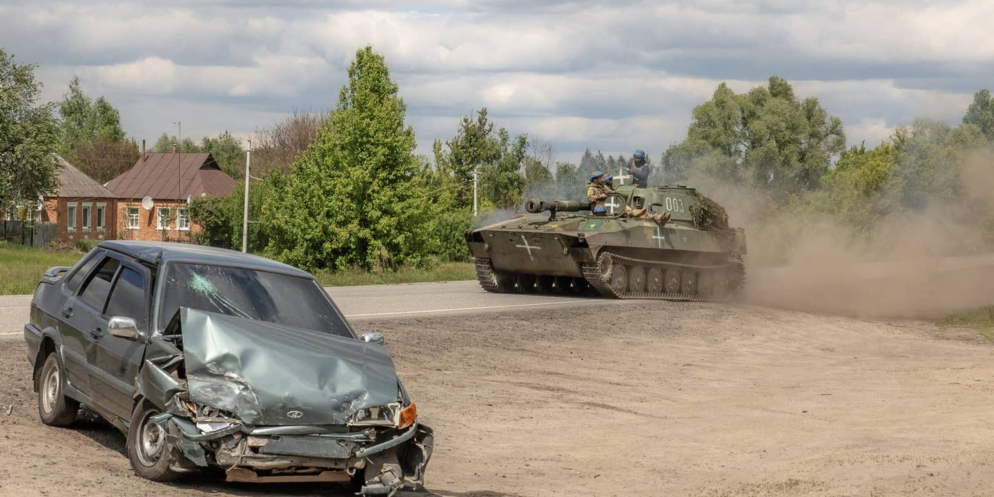 A Ukrainian self-propelled howitzer 2S1 Gvozdika drives past a damaged car on a road in the Vovchansk district, Kharkiv region, on May 12, 2024, amid the Russian invasion of Ukraine. Thousands of people have been evacuated from border areas in Ukraine's Kharkiv region, as Russia kept up constant strikes on a key town as part of a cross-border offensive, officials said on May 12, 2024. The surprise Russian attack across Ukraine's northeastern border began on Friday, with troops making small advances in an area from where they had been pushed back nearly two years ago.