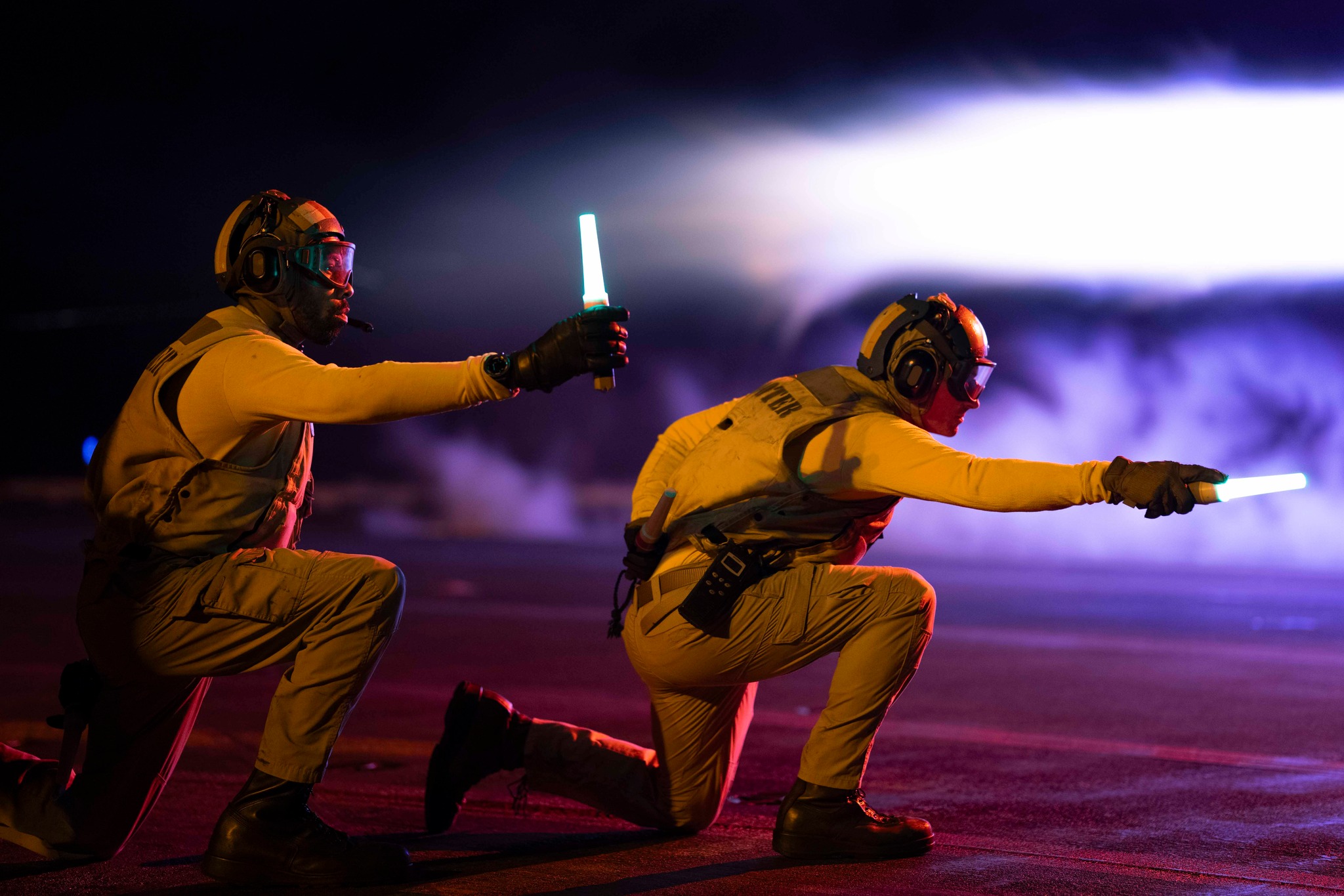 240117-N-VC924-2036 MIDDLE EAST (Jan. 17, 2024) U.S. Navy Lt. Justin Roberts, left and Lt. Charles Jinks signal to aircraft during flight operations aboard the aircraft carrier USS Dwight D. Eisenhower (CVN 69) Jan. 17, 2024. The Dwight D. Eisenhower Carrier Strike Group is deployed to the U.S. 5th Fleet area of operations to support maritime security and stability in the Middle East region. (U.S. Navy photo by Mass Communication Specialist 2nd Class Zachary Elmore)