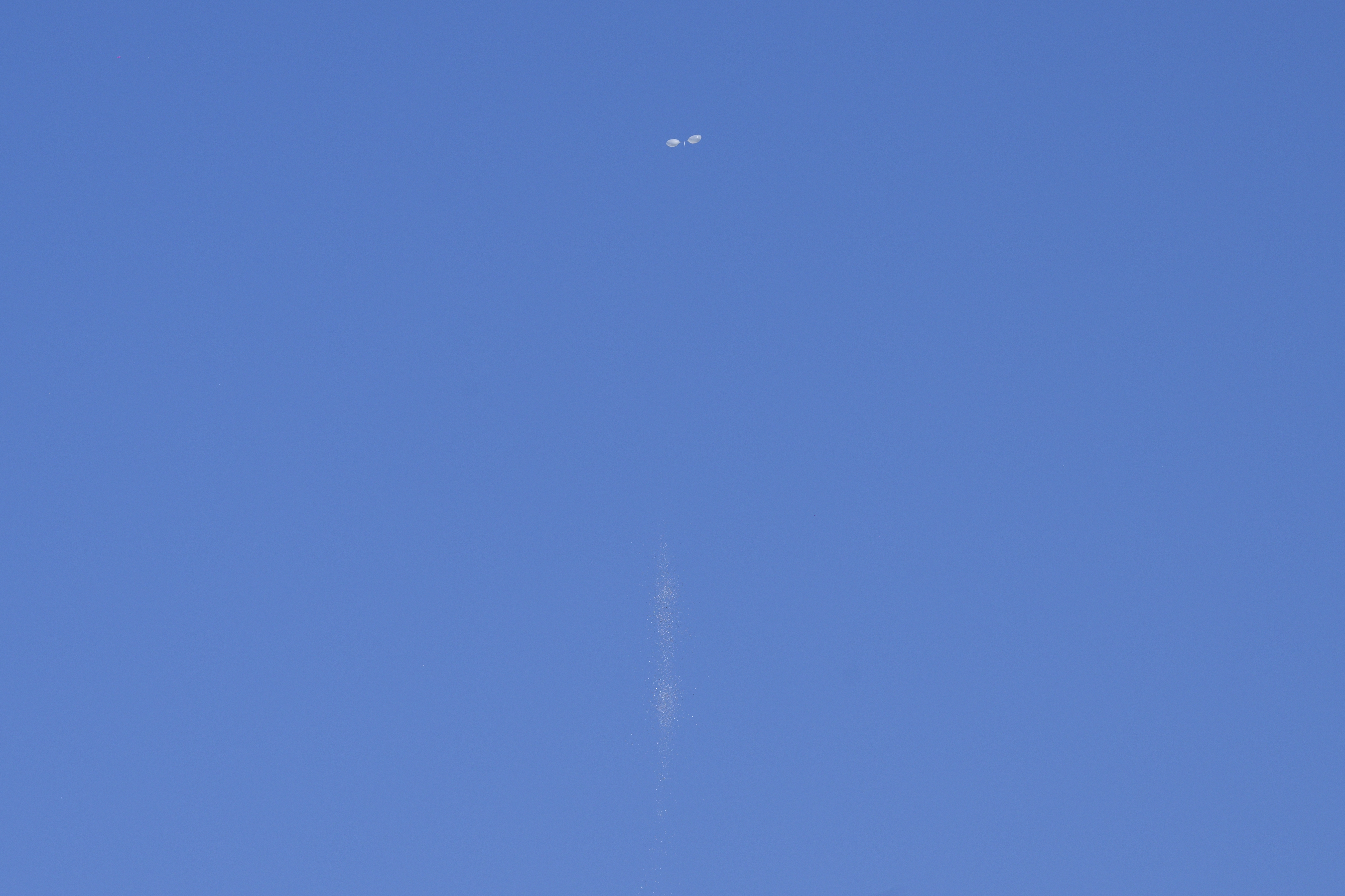 Pieces of garbage (bottom C) fall to the ground after a trash-carrying balloon launched across the border by North Korea burst in the sky above Seoul on October 4, 2024. Relations between the two Koreas are at one of their lowest points in years, with Pyongyang ramping up weapons tests and bombarding the South with balloons carrying rubbish, and Seoul suspending a military deal and resuming propaganda broadcasts in response. (Photo by ANTHONY WALLACE / AFP) (Photo by ANTHONY WALLACE/AFP via Getty Images)