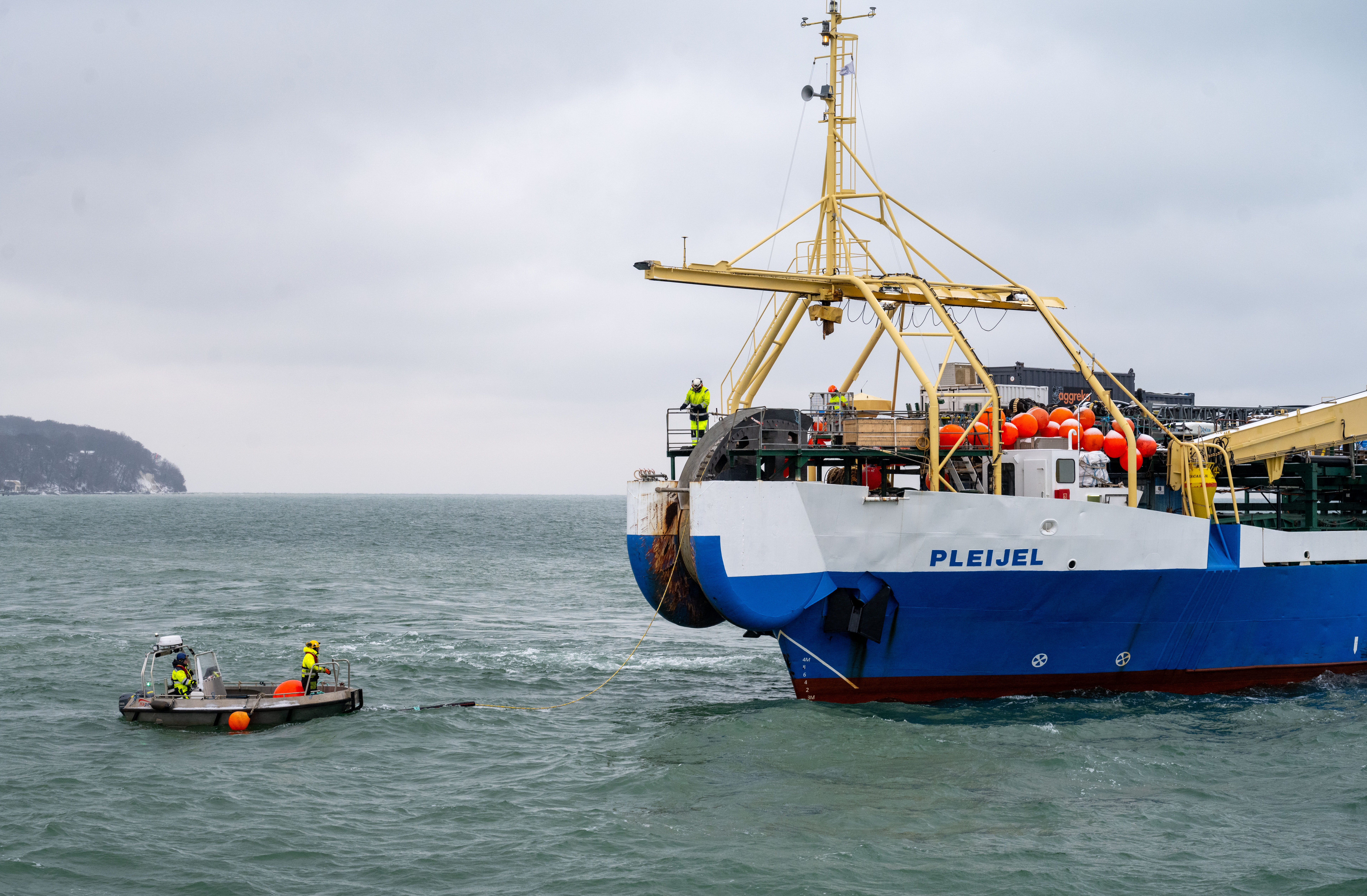 29 November 2023, Mecklenburg-Western Pomerania, Sassnitz: A fiber optic cable is pulled ashore from the cable-laying ship "Pleijel" at the entrance to the port of Sassnitz. After several weather-related delays, an 800-kilometre-long undersea cable from Scandinavia landed in Sassnitz on the island of Rügen on Wednesday. the yellow cable, which is about the thickness of a broomstick, will soon be connected to the GlobalConnect fiber optic network. Including land and sea routes, the cable for the digital high-speed highway is a total of 2,600 kilometers long, as GlobalConnect announced. Work began in fall 2021. Photo: Stefan Sauer/dpa (Photo by Stefan Sauer/picture alliance via Getty Images)