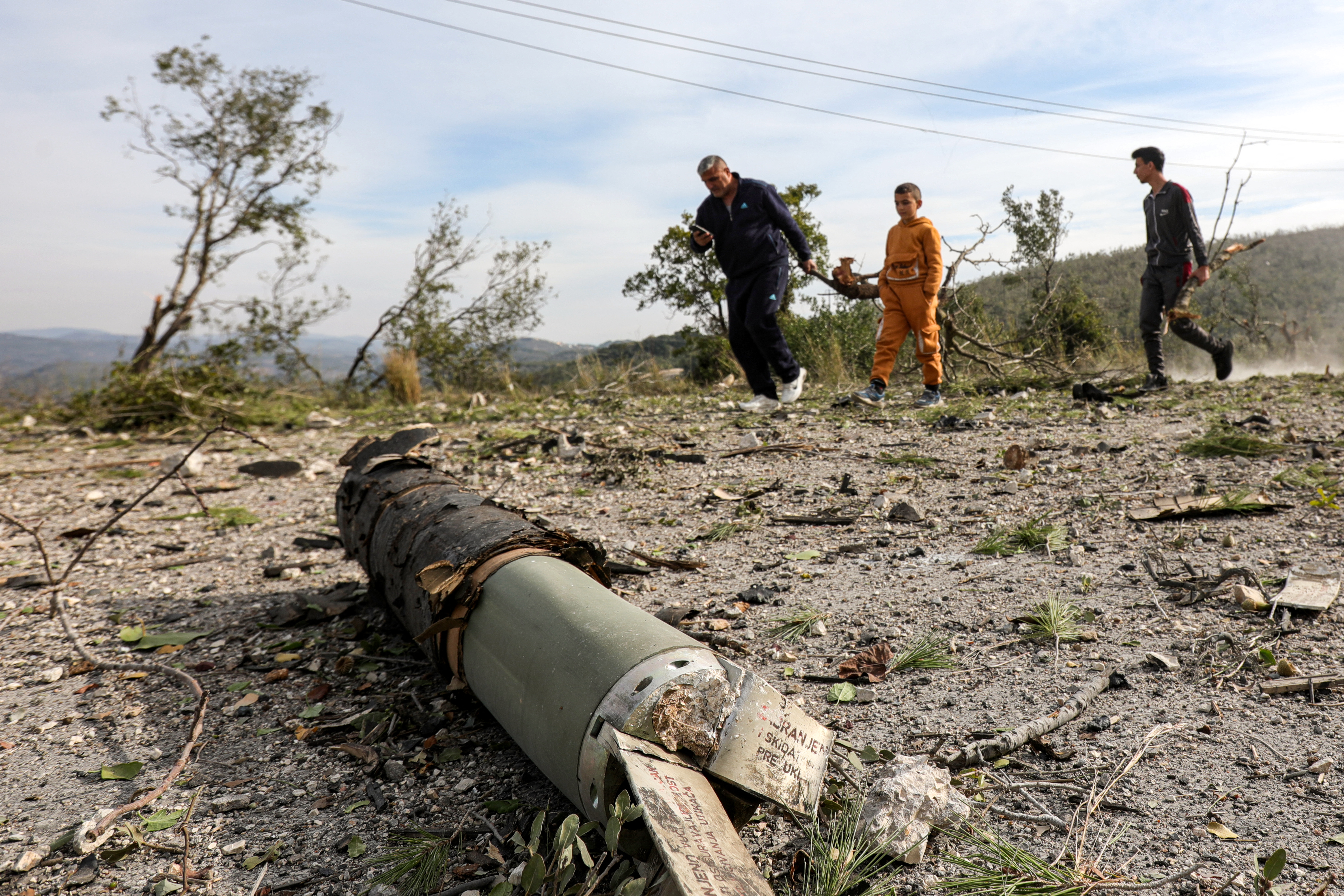 People walk past the fragment of a missile at the site of a Syrian army weapons depot that was hit by overnight Israeli bombardment on the outskirts of the village of Bmalkah in the countryside of Tartus in western Syria on December 16, 2024. A Syrian bunker complex outside the port of Tartus was ablaze and rocked by explosions on December 16 just hours after what the UK-based Syrian Observatory for Human Rights and local residents said was an intense wave of Israeli air strikes. (Photo by Bakr ALKASEM / AFP) (Photo by BAKR ALKASEM/AFP via Getty Images)
