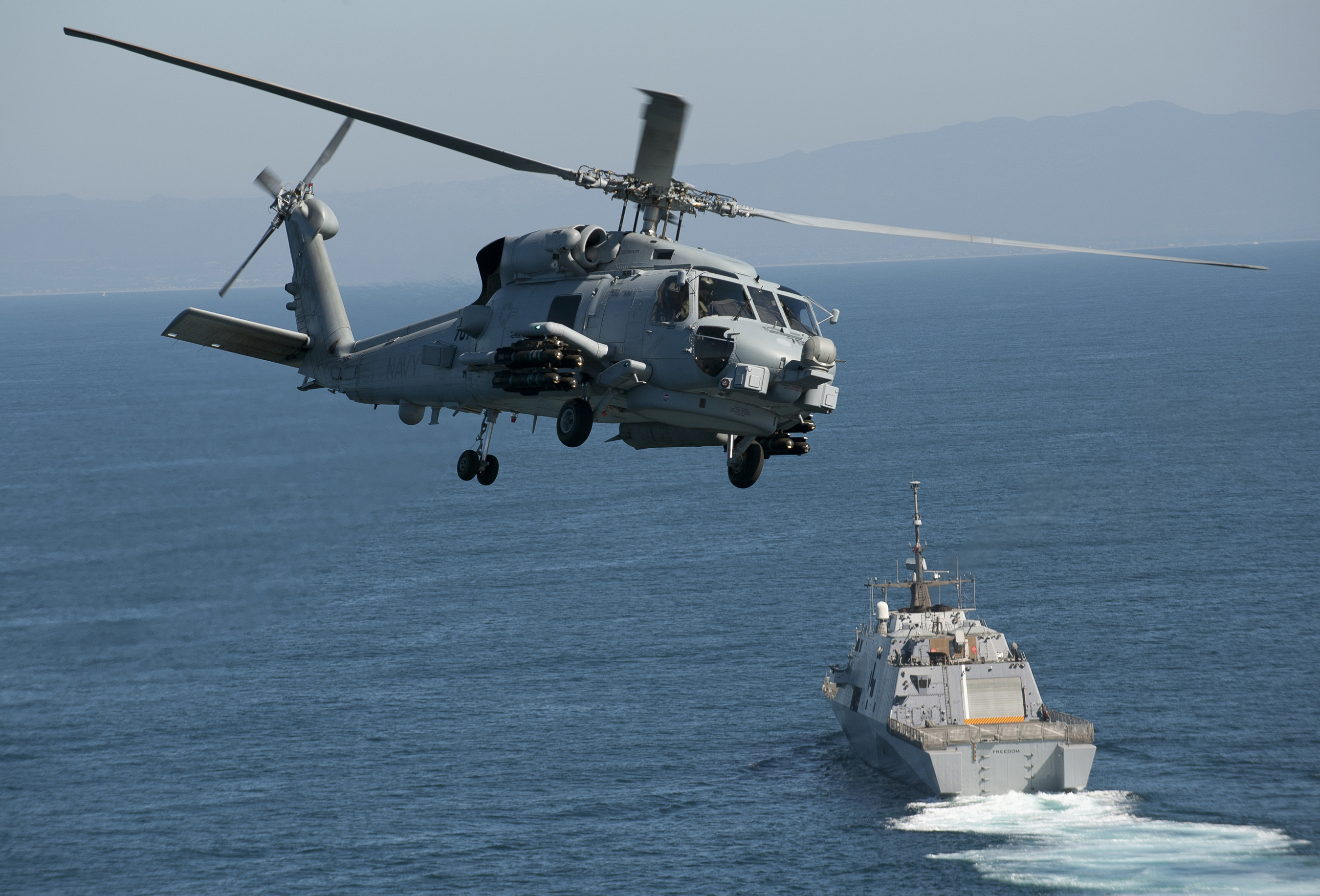 An MH-60R Seahawk assigned to Helicopter Maritime Strike Squadron (HSM) 73 flies near the littoral combat ship USS Freedom (LCS 1). This is the first fleet MH-60R to operate with a Right Hand Extended Pylon (RHEP) and a full compliment of eight AGM-114 Hellfire Captive Air Training Missiles as it joins Freedom for sea trials off the coast of Southern California. Freedom, the lead ship of the Freedom variant of LCS, is expected to deploy to Southeast Asia this spring. (U.S. Navy photo by Mass Communication Specialist 1st Class James R. Evans/Released)