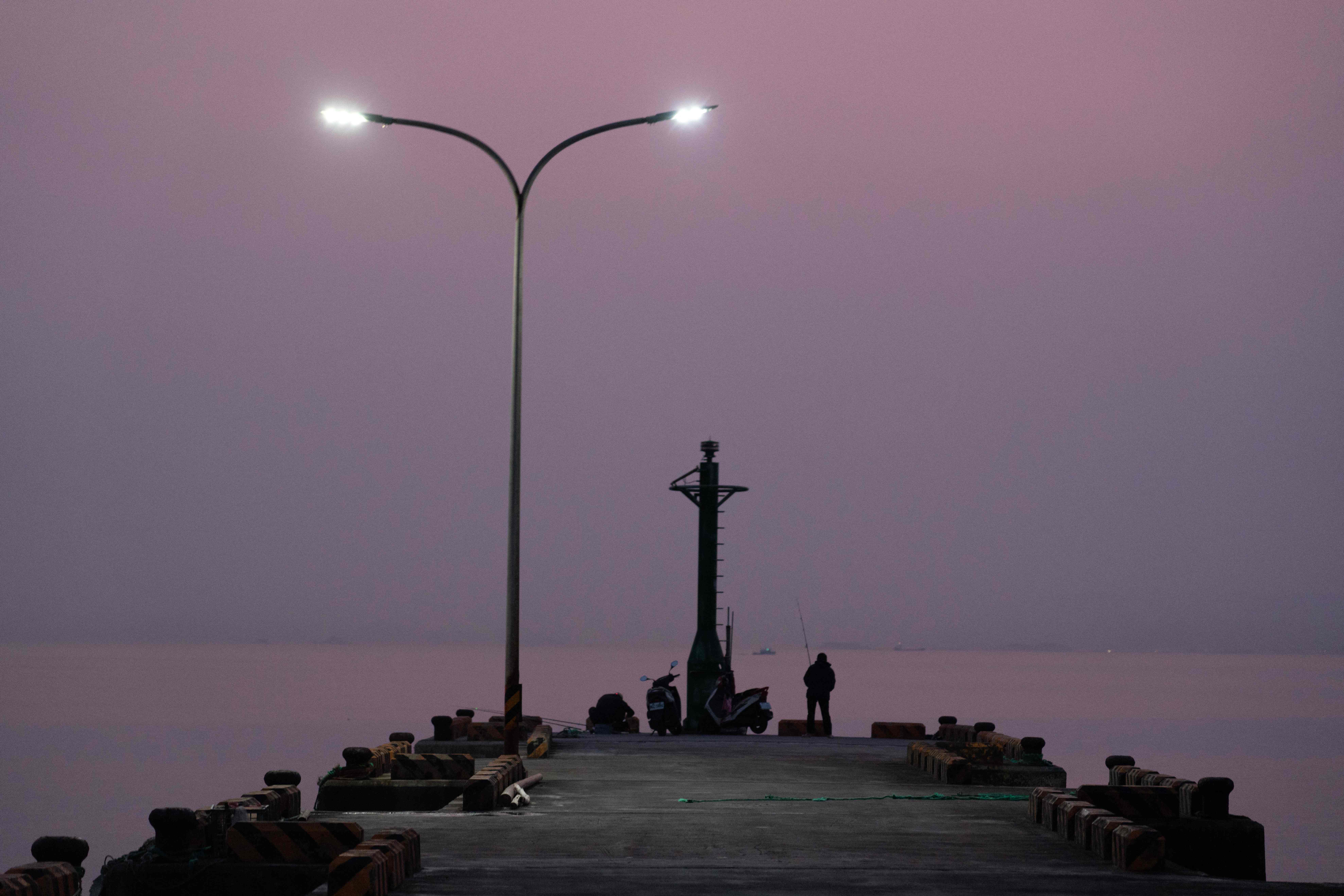 TOPSHOT - This picture taken on April 10, 2023 shows fishermen on a jetty at a harbour on Beigan island in Taiwan's Matsu archipelago. - Hostel worker Wang Chuang-jen struggled to contact his guests arriving on the tiny Matsu archipelago in February after two undersea cables were cut, an incident that has forced Taiwan to reckon with its digital vulnerability. (Photo by Jack MOORE / AFP) / To go with AFP story Taiwan-China-satellite-telecommunication, FOCUS by Yan Zhao and Jack Moore with Amber Wang in Taipei (Photo by JACK MOORE/AFP via Getty Images)