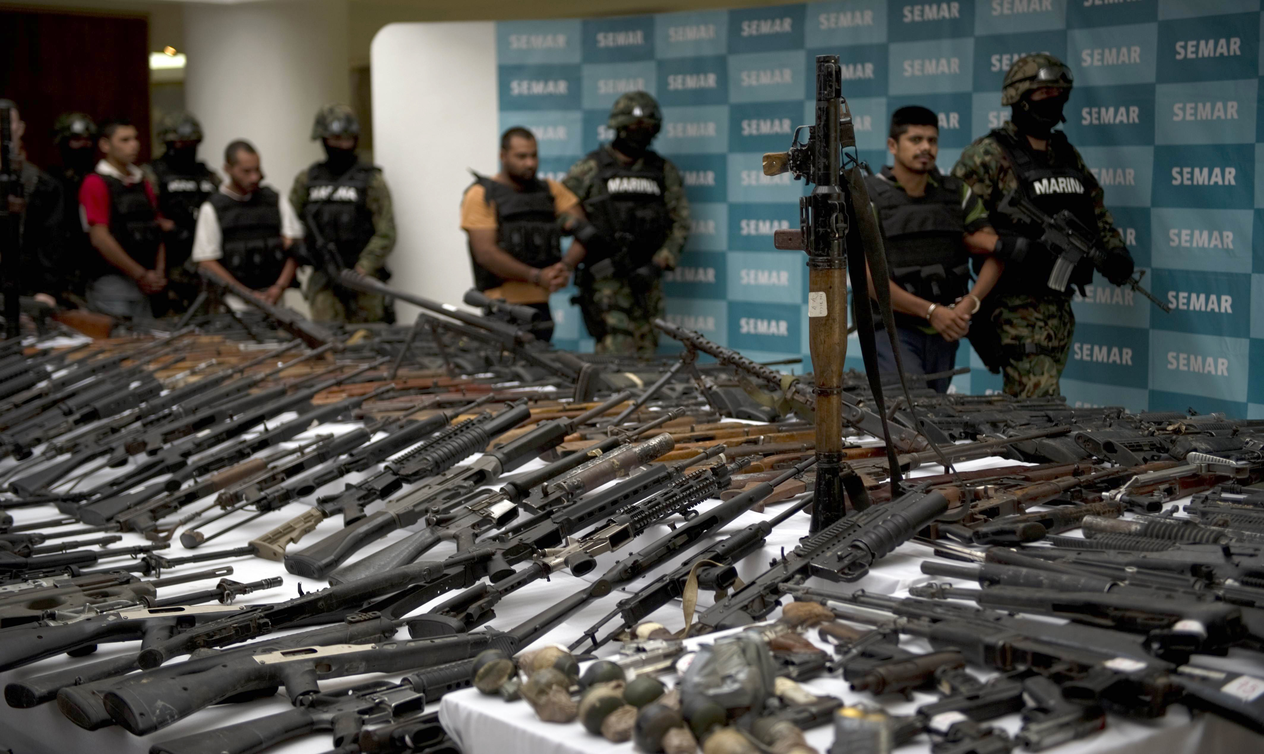 Mexican marines escort five alleged drug traffickers of the Zeta drug cartel in front of an RPG-7 rocket launcher, hand grenades, firearms, cocaine and military uniforms seized to alleged members of the Zetas drug traffickers cartel and presented to press on June 9, 2011 at the Navy Secretaryship in Mexico City. Fiven men were arrested and more than two hundred rifles, eleven pistols, military uniforms, differents caliber ammunitions and more than 200 kg of cocaine were seized in the Coahuila and Nuevo Leon States by the Navy. AFP PHOTO/ Yuri CORTEZ (Photo credit should read YURI CORTEZ/AFP via Getty Images)