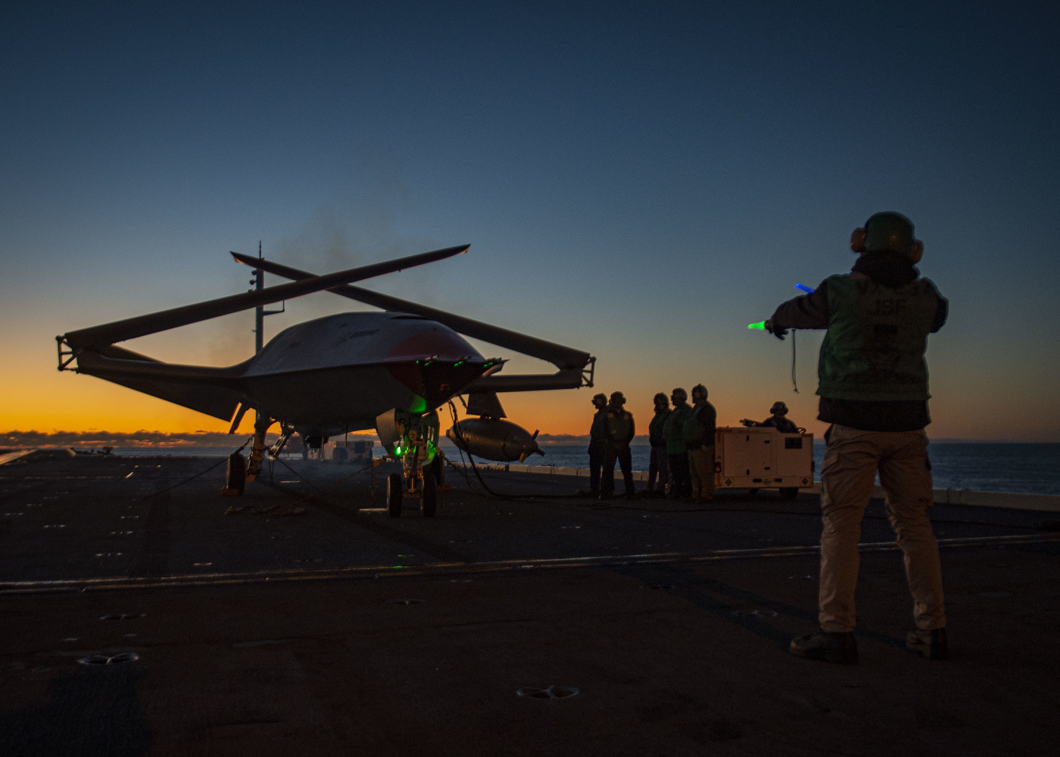 A Boeing unmanned MQ-25 aircraft is given operating directions on the flight deck aboard the aircraft carrier USS George H.W. Bush (CVN 77). The MQ-25 will be the world’s first operational, carrier-based unmanned aircraft and is integral to the Air Wing of the Future Family of Systems (AWotF FoS). Its initial operating capability (IOC) as an aerial refueling tanker will extend the range, operational capability and power projection of the carrier air wing (CVW) and carrier strike group (CSG). GHWB is operating in the Atlantic Ocean in support of naval operations to maintain maritime stability and security in order to ensure access, deter aggression and defend U.S., allied and partner interests. (U.S. Navy photo by Mass Communication Specialist 3rd Class Brandon Roberson)