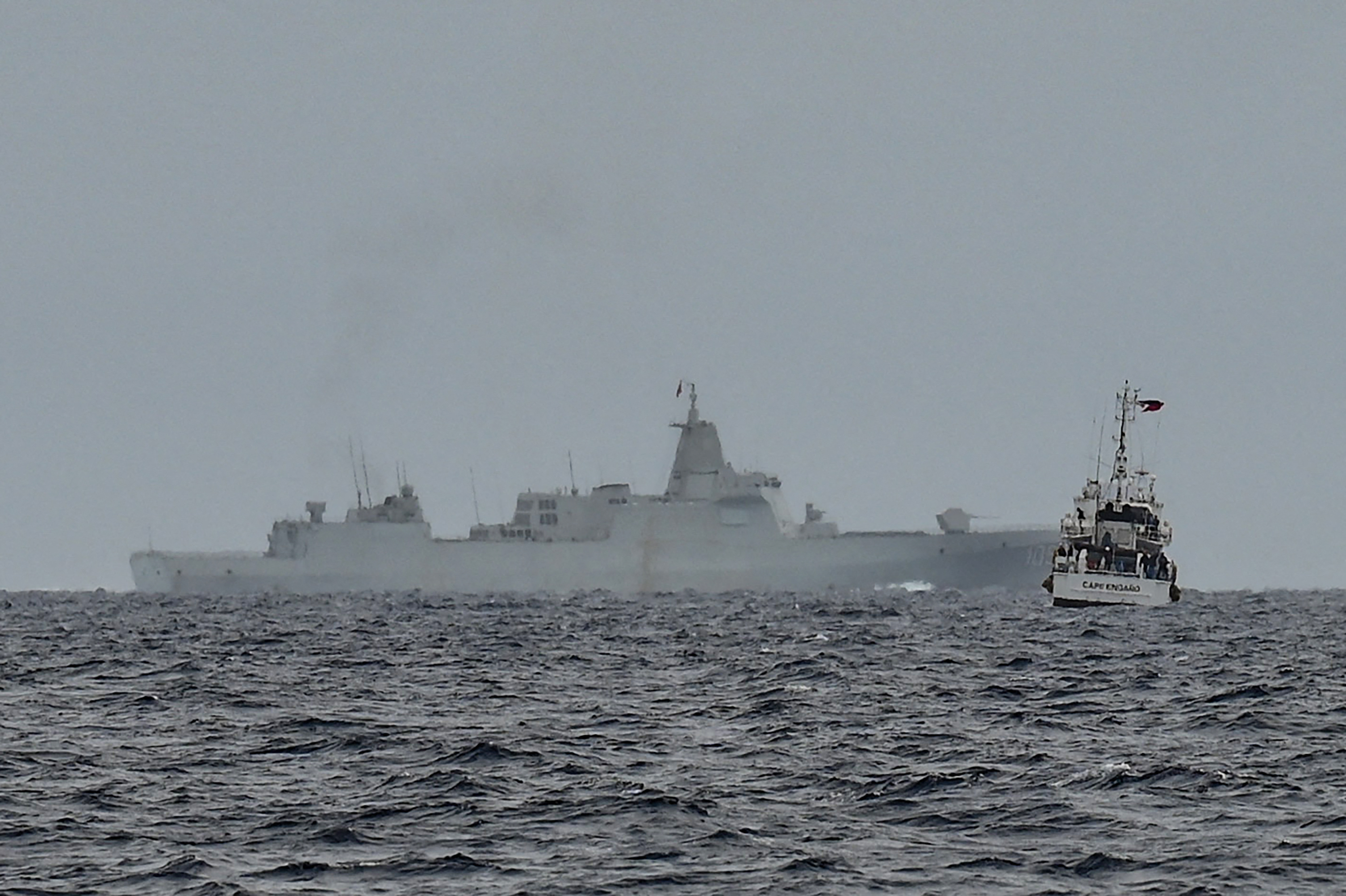 A vessel identified by the Philippine Coast Guard as a Chinese navy ship (background C) is seen past the Philippine Coast Guard ship BRP Cape Engano (R), during a supply mission to Sabina Shoal in disputed waters of the South China Sea on August 26, 2024. Sailors aboard two Philippine Coast Guard vessels crashed through South China Sea waves trying to bring food and other supplies to colleagues holed up inside a remote ring of reefs, as Chinese ships shadowed them. (Photo by JAM STA ROSA / AFP) (Photo by JAM STA ROSAJAM STA ROSA/AFP via Getty Images)