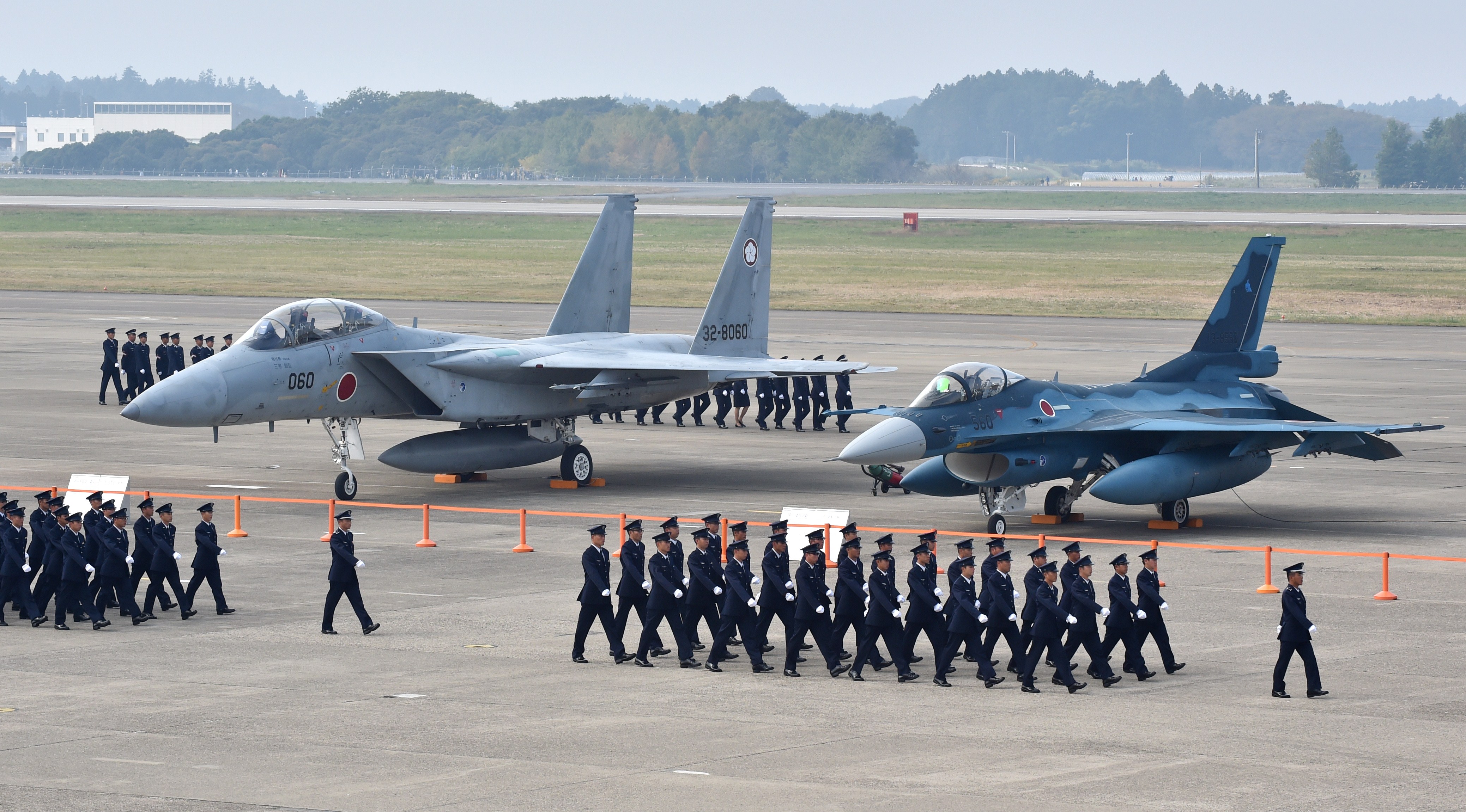 Air servicemen of the Japan Self-Defense Force walk past a F-15J/DJ fighter aircraft (L) and a F-2 A/B fighter aircraft (R) on a runway prior to a review ceremony at the Japan Air Self-Defense Force's Hyakuri air base in Omitama, Ibaraki prefecture on October 26, 2014. Japan's Prime Minister Shinzo Abe spoke at a military review on October 26, renewing his pledge to pursue the controversial shift in the nation's military stance. AFP PHOTO / KAZUHIRO NOGI (Photo credit should read KAZUHIRO NOGI/AFP via Getty Images)