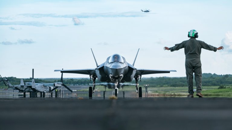 A U.S. Marine Corps plane captain assigned to the Marine Fighter Attach Squadron 225 (VMFA-225) signals to a pilot in a F35B Lightning II as it taxis on the flightline after landing in the U.S. Southern Command Area of Responsibility, Sept. 13, 2025. U.S. military forces are deployed to the Caribbean in support of the U.S. Southern Command mission, Department of War-directed operations, and the president’s priorities. (U.S. Air Force photo by Senior Airman Katelynn Jackson)