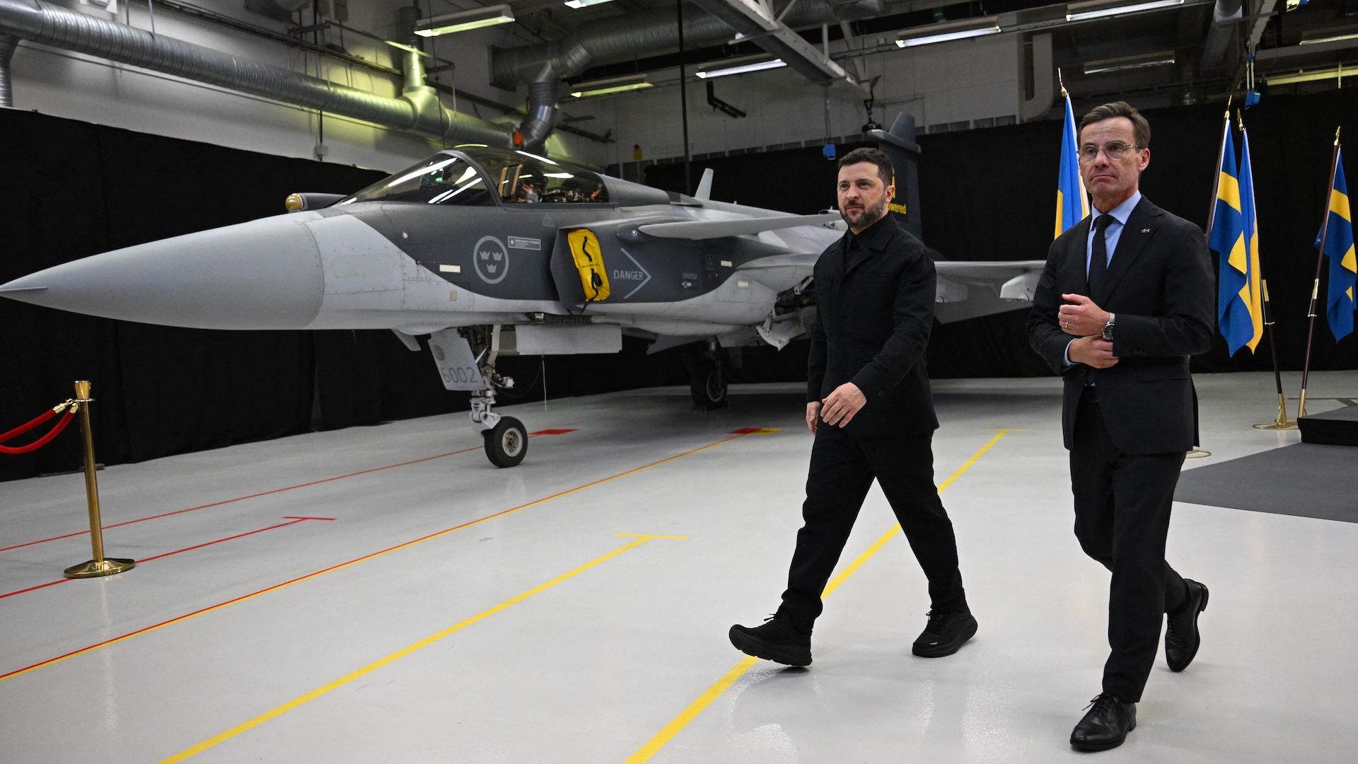 Swedish Prime Minister Ulf Kristersson (R) and Ukrainian President Volodymyr Zelensky walk past a Gripen fighter jet after they delivered a joint press conference in Linkoping, Sweden, on October 22, 2025, after talks on Russia's ongoing of aggression against Ukraine and the countries' deepening defense cooperation. Swedish Prime Minister Ulf Kristersson said on october 22 that Sweden and Ukraine had signed a letter of intent to develop air capabilities, which could see Ukraine buy up to 150 Gripen fighter jets.