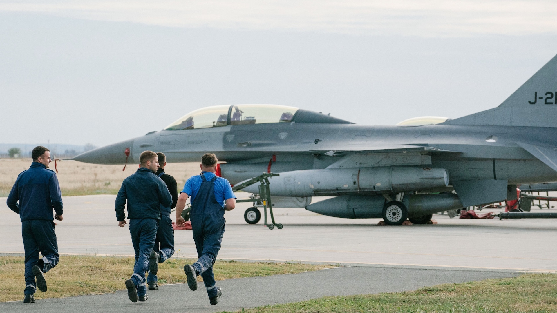 A group of men run on the tarmac during the opening ceremony of the European F-16 Training Center at the 86th Romanian Military Airbase in Fetesti, Romania, on November 13, 2023.