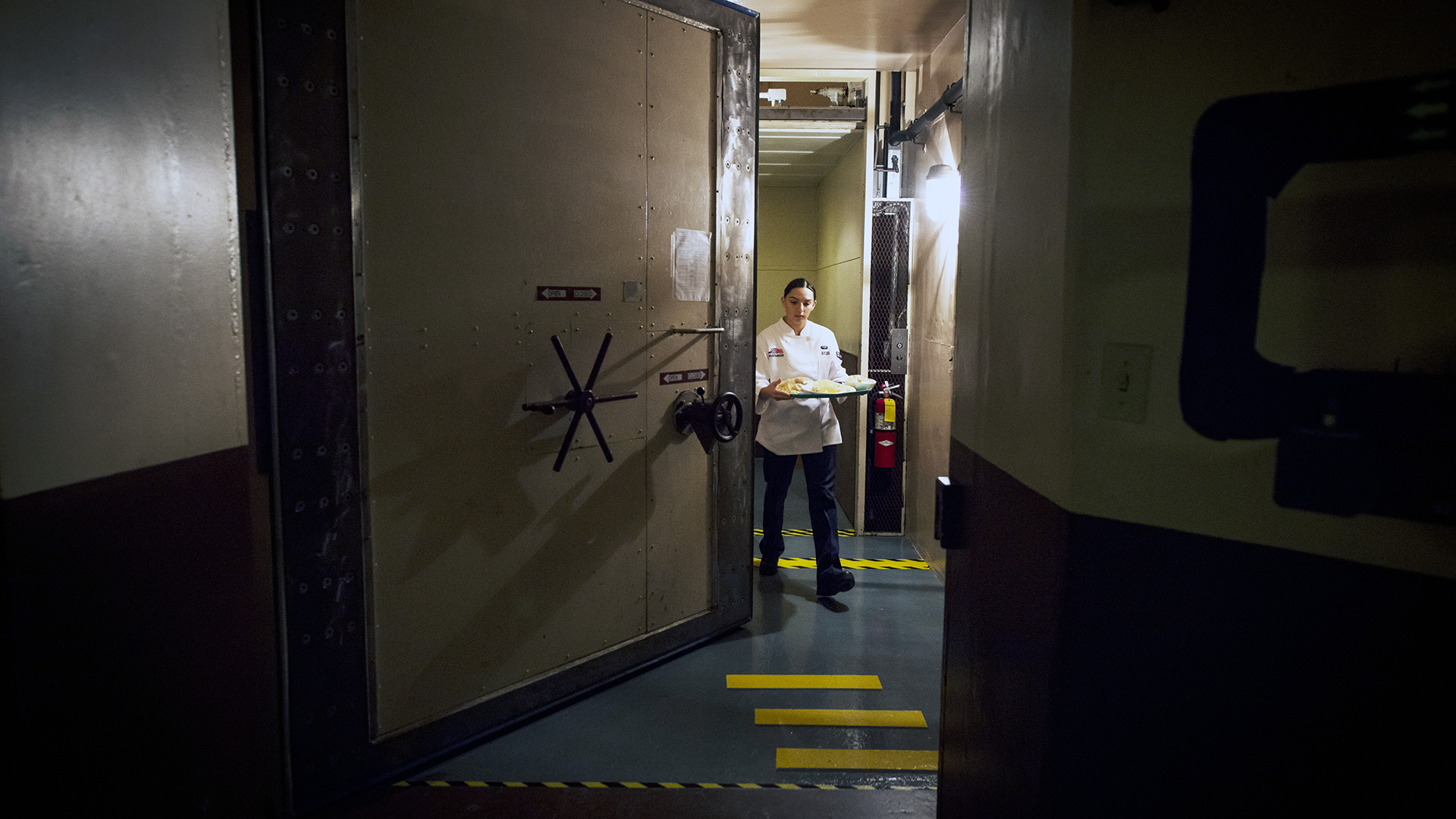 Airman 1st Class Alexandra Ayub walks through a blast door to deliver a meal to the missileers manning the launch control center which is approximately 60 feet beneath the missile alert facility. (U.S. Air Force photo/Staff Sgt. Andrew Lee)