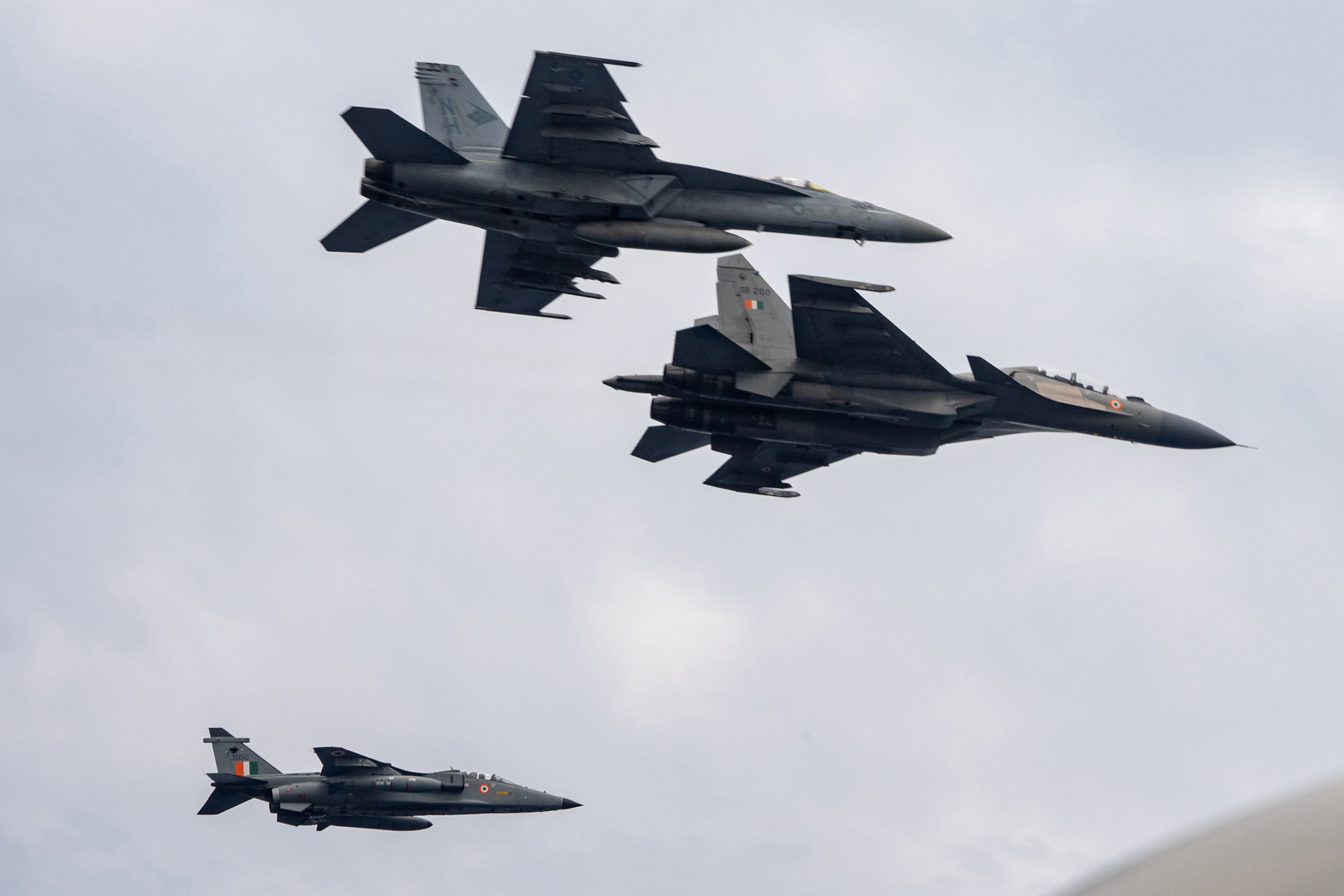 INDIAN OCEAN (March 28, 2021) – An F/A-18E Super Hornet, assigned to the “Blue Diamonds” of Strike Fighter Squadron (VFA) 146, top, flies in formation with an Indian Air Force Su-30MKI, middle, and Jaguar over the aircraft carrier USS Theodore Roosevelt (CVN 71) March 28, 2021. The Theodore Roosevelt Carrier Strike Group is on a scheduled deployment to the U.S. 7th Fleet area of operations. As the U.S. Navy’s largest forward-deployed fleet, 7th Fleet routinely operates and interacts with 35 maritime nations while conducting missions to preserve and protect a free and open Indo-Pacific Region. (U.S. Navy photo by Mass Communication Specialist 3rd Class Carlos W. Hopper)