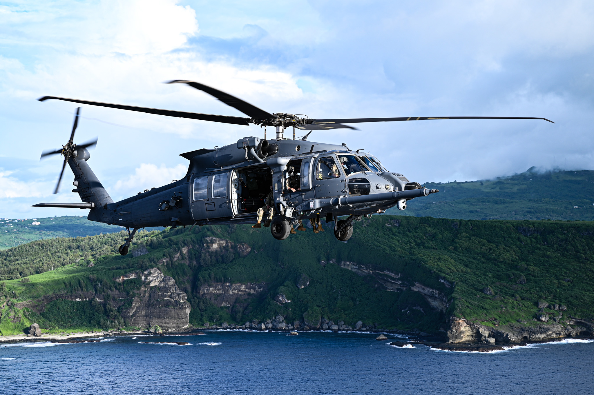 A U.S. Air Force HH-60W Jolly Green II helicopter from the 563rd Rescue Group flies ahead of the Liberation Day celebration during exercise Resolute Force Pacific in Rota, Northern Mariana Islands, July 20, 2025. REFORPAC is part of the first-in-a-generation Department-Level Exercise series, employing more than 400 Joint and coalition aircraft and more than 12,000 members at more than 50 locations across 3,000 miles. (U.S. Air Force photo by Senior Airman Andrew Garavito)