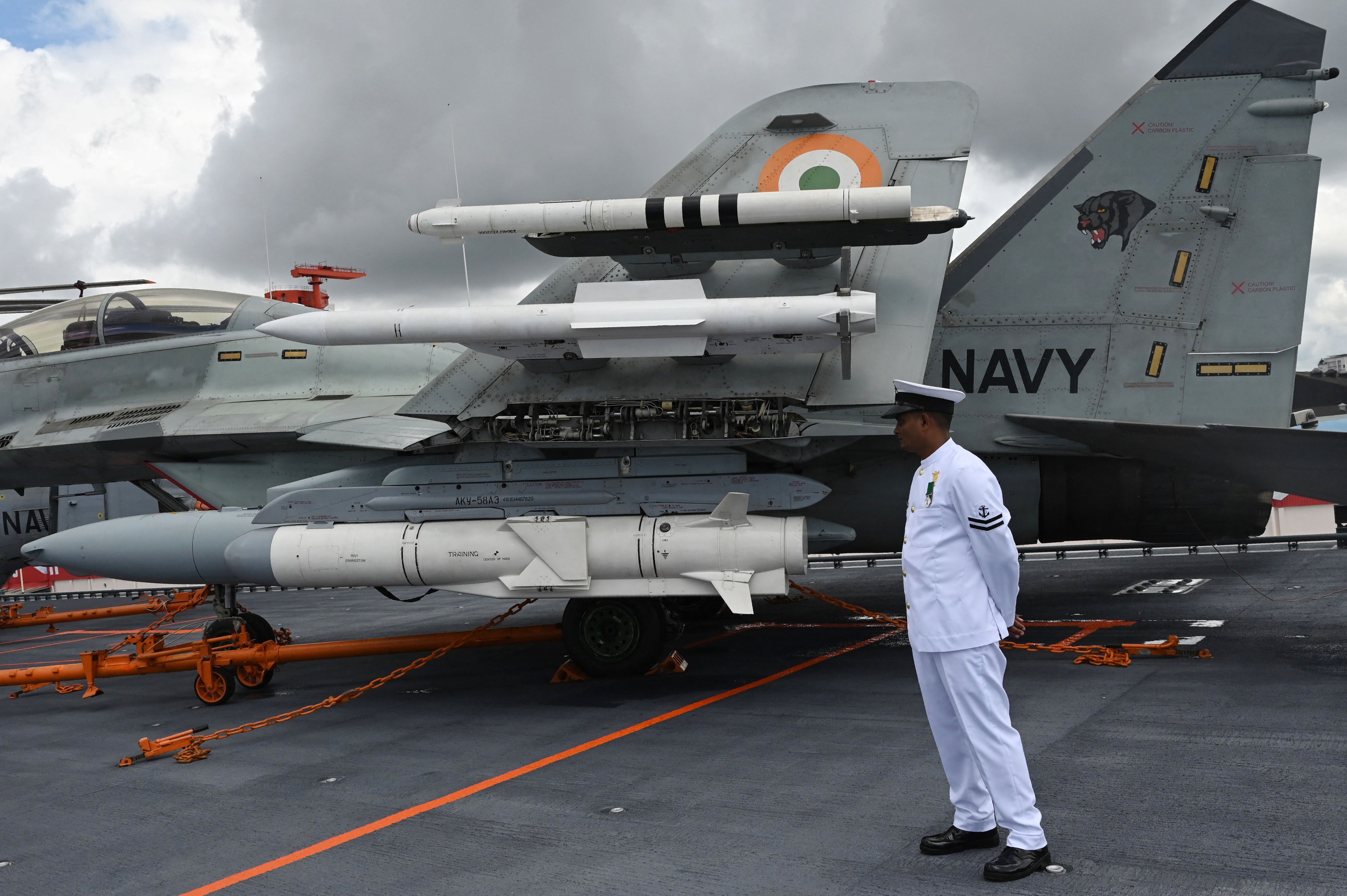 An Indian Navy officer stands next to a Mig 29 fighter jet on the deck of the Indian indigenous aircraft carrier INS Vikrant during its commissioning at Cochin Shipyard in Kochi on September 2, 2022. - India debuted its first locally made aircraft carrier on September 2, a milestone in government efforts to reduce its dependence on foreign arms and counter China's growing military assertiveness in the region. (Photo by Arun SANKAR / AFP) (Photo by ARUN SANKAR/AFP via Getty Images)