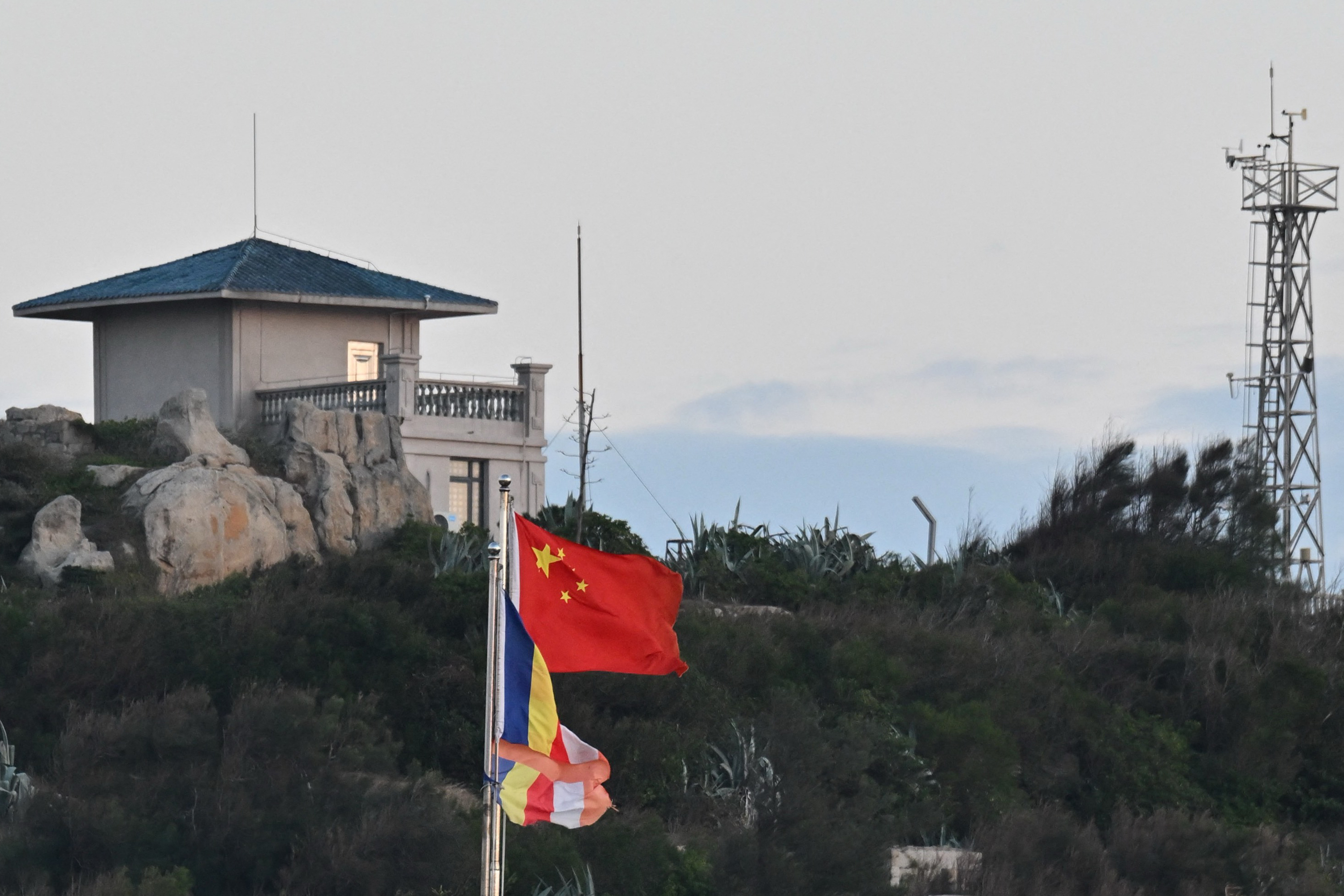 The Chinese flag (C) is seen on Pingtan island, the closest point to Taiwan, in eastern China's Fujian province on December 29, 2025. China launched live-fire drills around Taiwan on December 29 that it said would simulate a blockade of the self-ruled island's key ports, prompting Taipei to condemn Beijing's "military intimidation". (Photo by ADEK BERRY / AFP via Getty Images)