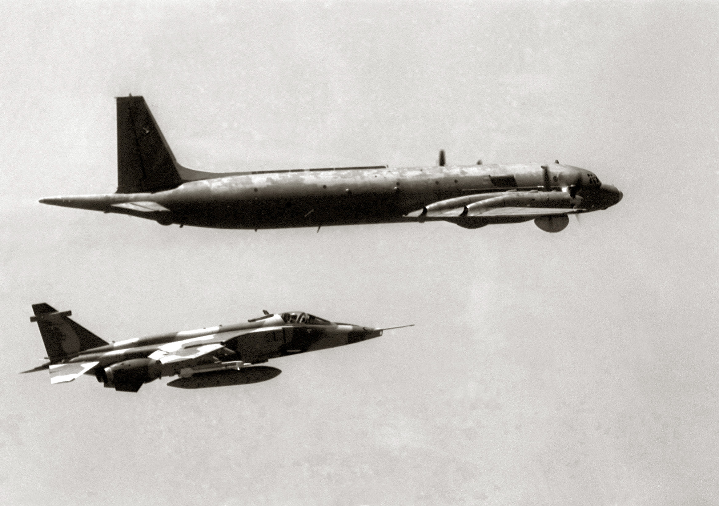 An air-to-air right side view of a Sepecat Jaguar aircraft approaching a Soviet I1-38 May maritime patrol aircraft.