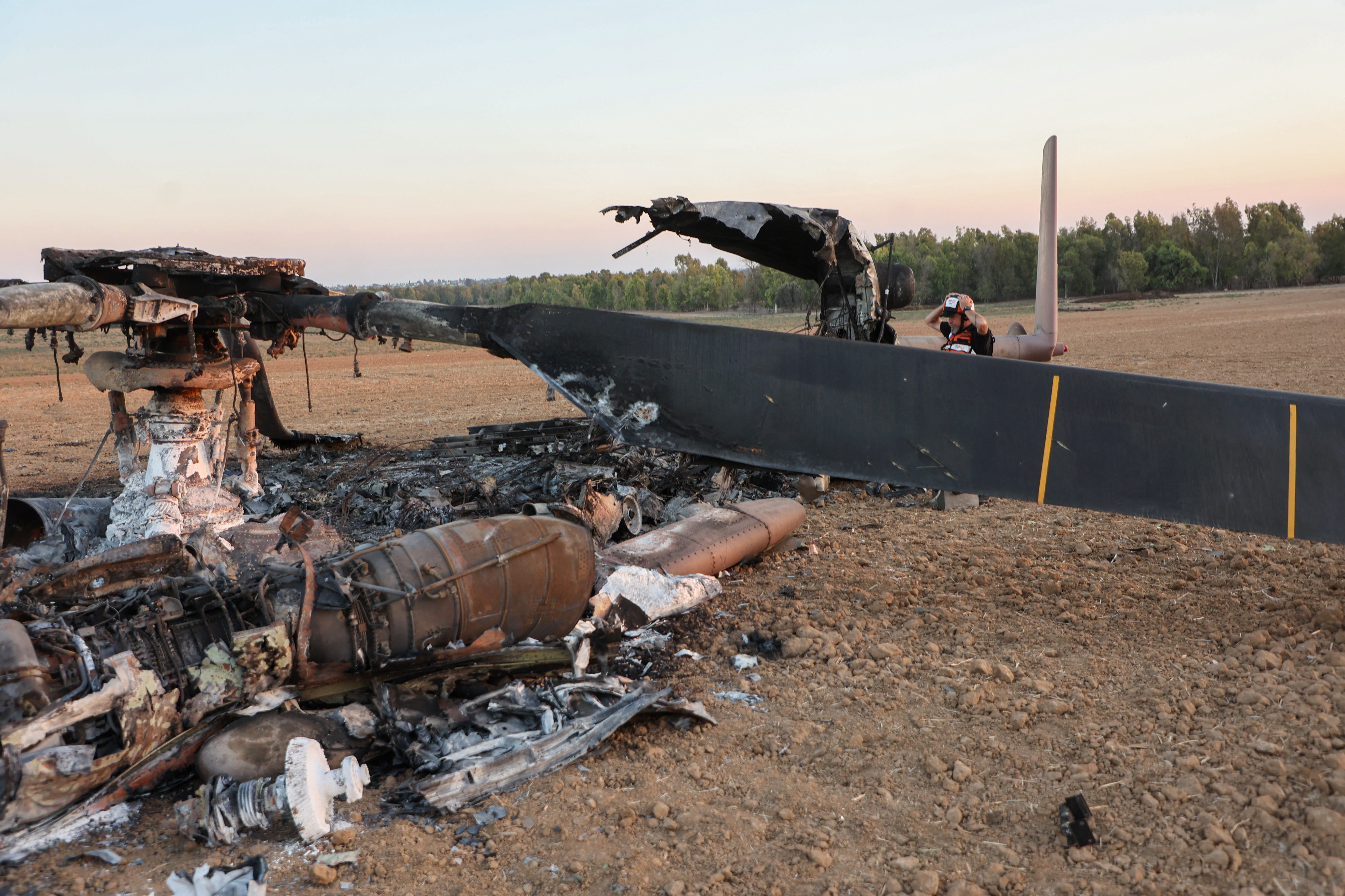 A member of Israeli rescue services searches the carcass of an Israeli CH-53 "Yasur" helicopter on October 15, 2023, which was reportedly hit by Hamas militants during their attack a week earlier and fell on the Israeli side of the northern Gaza border. More than one million people have been displaced in the Gaza Strip in the last week, the UN said on October 15, after sustained Israeli bombardment and warnings about a ground attack against Hamas commanders. (Photo by GIL COHEN-MAGEN / AFP) (Photo by GIL COHEN-MAGEN/AFP via Getty Images)
