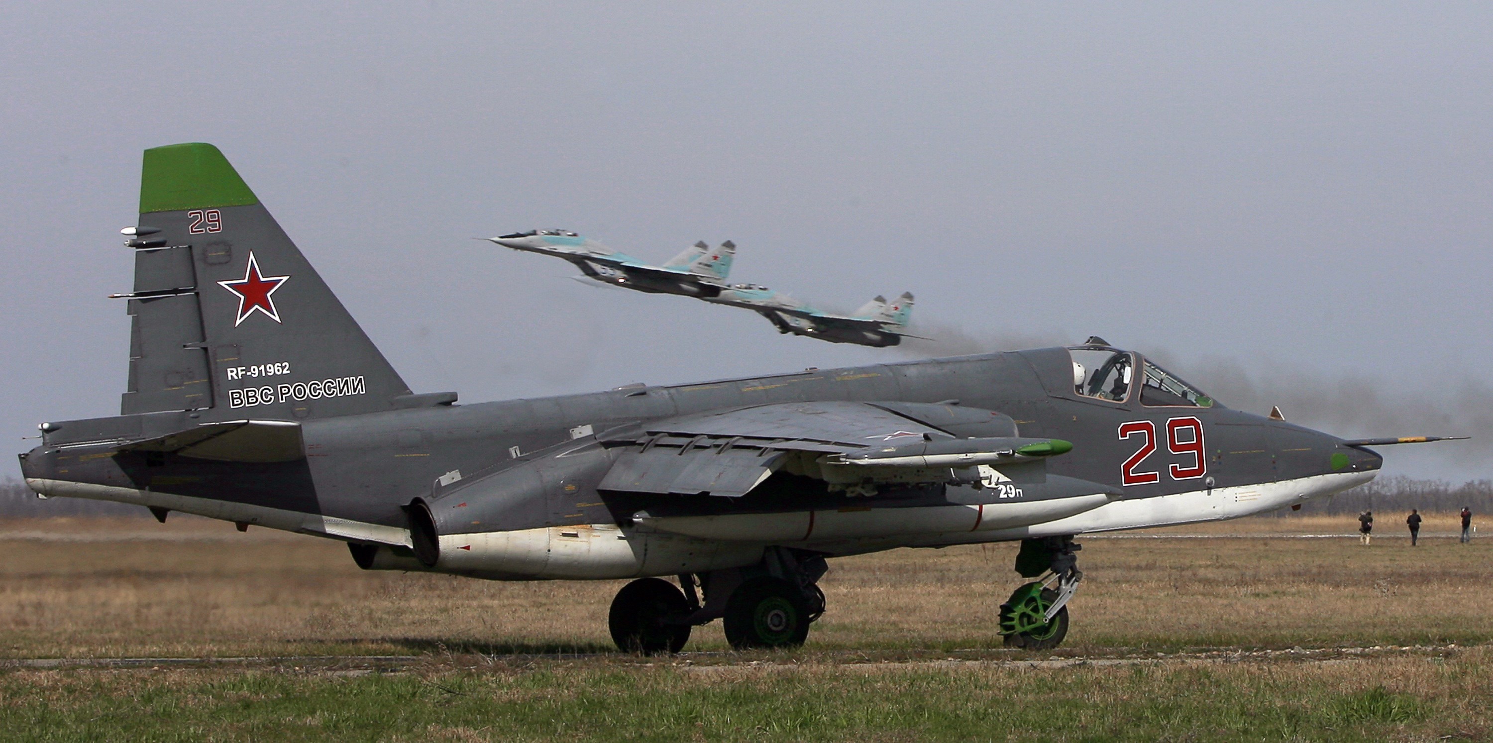 Russian SU 25 SM ground attack aircraft (ground) and MIG 29 jet fighters (taking off) attend a training session at Primorkso-Akhtarsk, Krasnodar region on March 26, 2015 ahead of the Russian commemoration of the 70th anniversary of the capitulation of Nazi Germany in 1945. AFP PHOTO / SERGEY VENYAVSKY (Photo credit should read SERGEY VENYAVSKY/AFP via Getty Images)