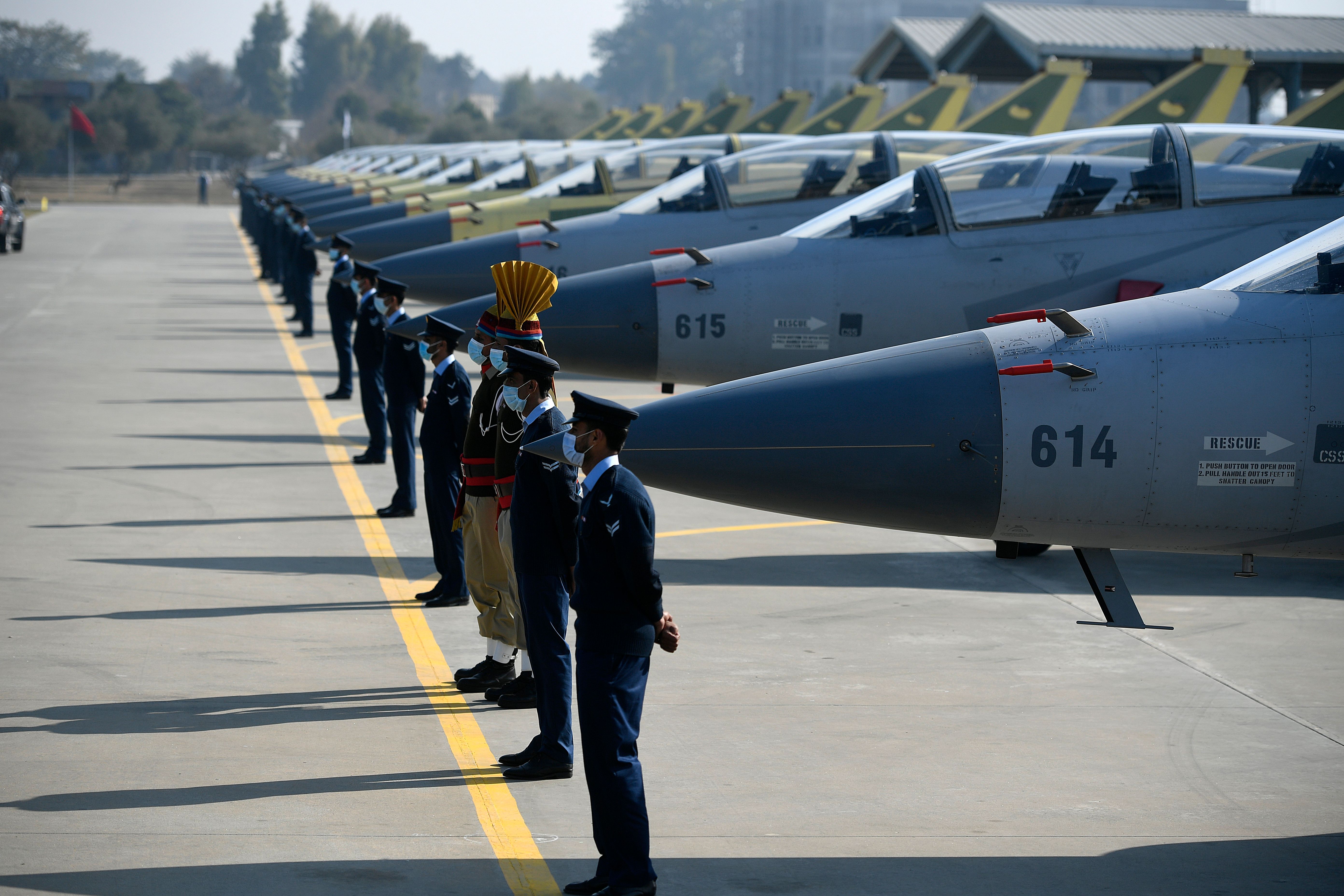 Pakistani Air Force personnel stand guard in front of fourteen Dual-seat JF-17B multi-role aircraft rolled out at a ceremony which coincided with the launch of JF-17 Block-III aircraft at the Pakistan Aeronautical Complex in Kamra, west of the capital Islamabad on December 30, 2020. (Photo by Aamir QURESHI / AFP) (Photo by AAMIR QURESHI/AFP via Getty Images)
