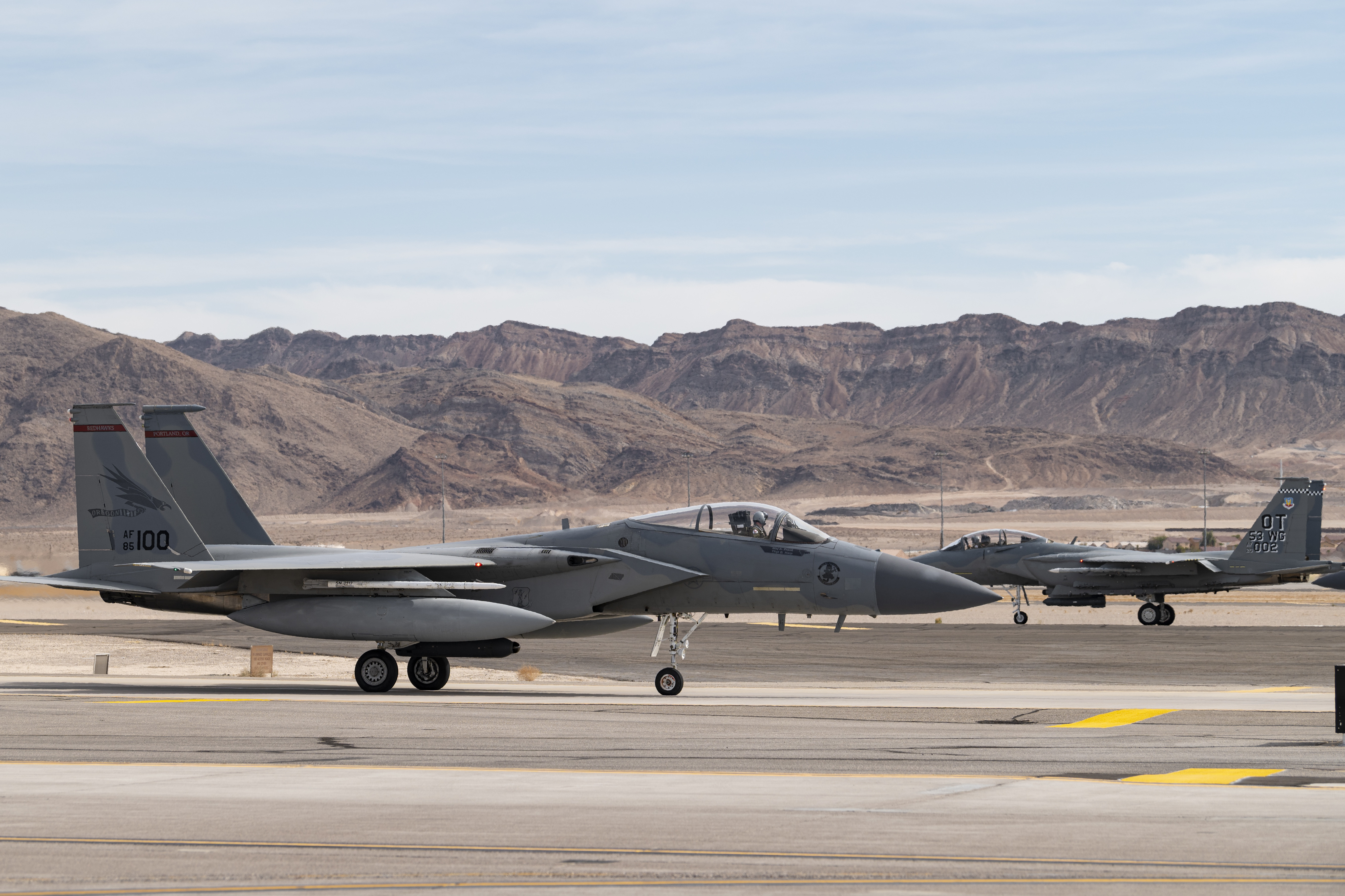 An F-15EX Eagle II Fighter Jet assigned to the 85th Test and Evaluation Squadron, Eglin Air Force Base, Florida, takes off and an F-15C Eagle assigned to the 123rd Fighter Squadron, Portland Air National Guard Base, Oregon, taxis to the runway at Nellis Air Force Base, Nevada, Oct. 20, 2021. Aircraft from Nellis AFB, Eglin AFB Florida, and the Oregon Air National Guard are providing support for the Test and Evaluation of the F-15EX in operationally realistic scenarios to determine how effective and suitable the aircraft is at accomplishing its air-to-air mission for future Air Force use. (U.S. Air Force photo by William R. Lewis)