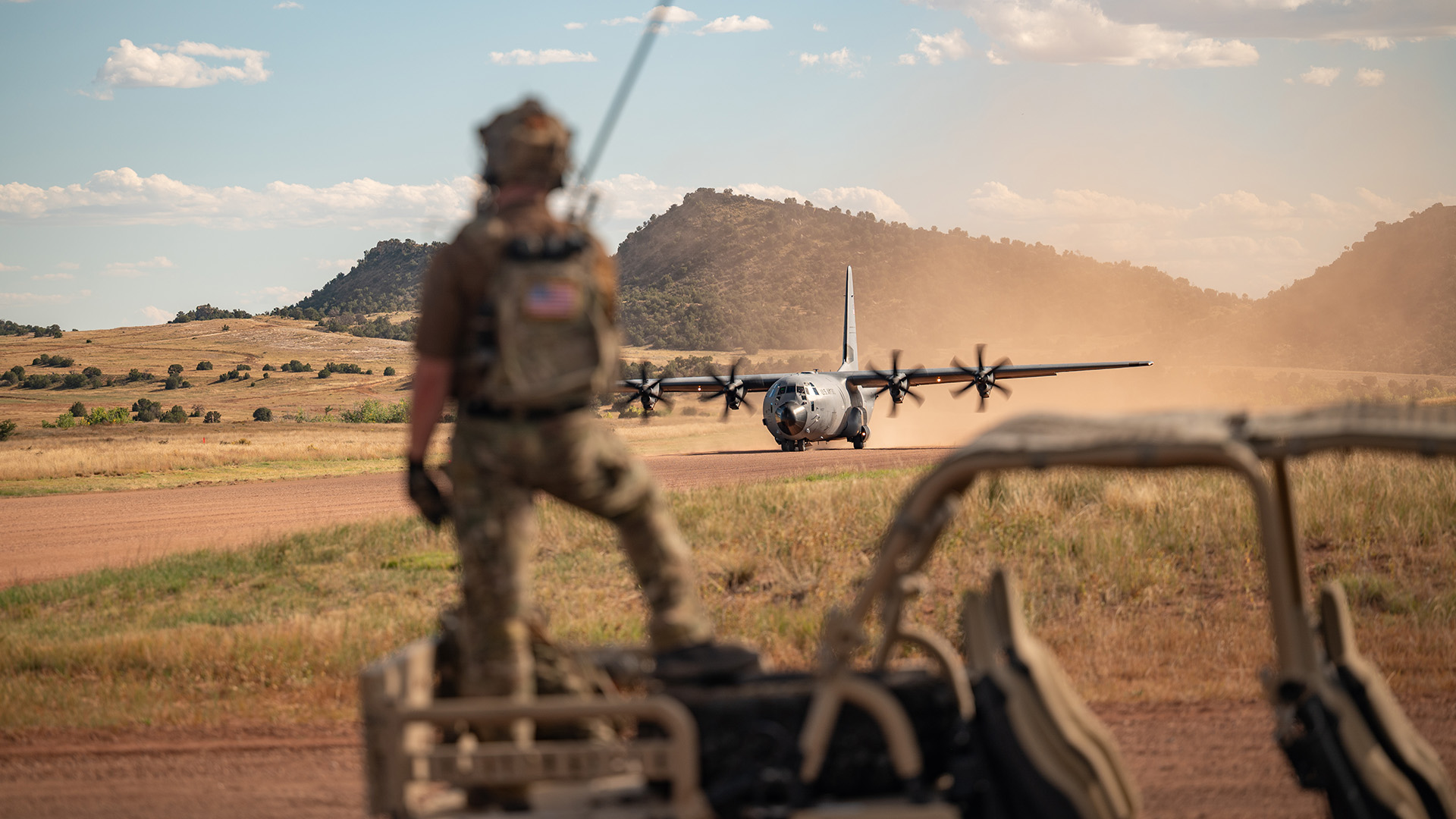 U.S. Air Force Tech. Sgt. Jacob Logsdon, 66th Weapons Squadron (WPS) combat controller, communicates with pilots of a C-130J Super Hercules prior to takeoff from a dirt runway during a U.S. Air Force Weapons School mission at Red Devil Landing Zone, Colorado, Oct. 3, 2025. The 29th and 66th WPS conducted an airdrop and evacuation in high-altitude mountain conditions, challenging students to coordinate across air and ground elements and plan complex objective areas that support joint mission success. (U.S. Air Force photo by Airman 1st Class Jennifer Nesbitt)