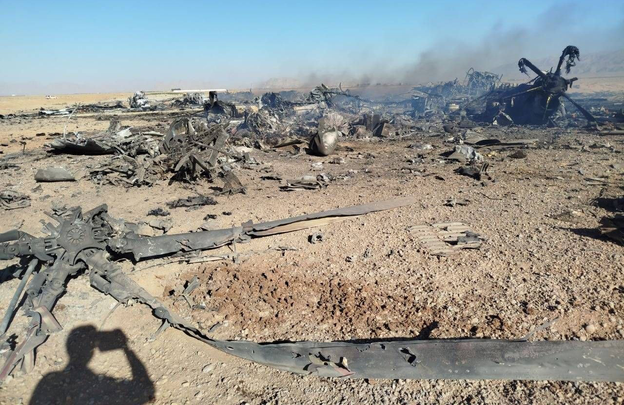 بدنه سوخته C-130 در پس‌زمینه و دکل روتور H-6 در پیش‌زمینه