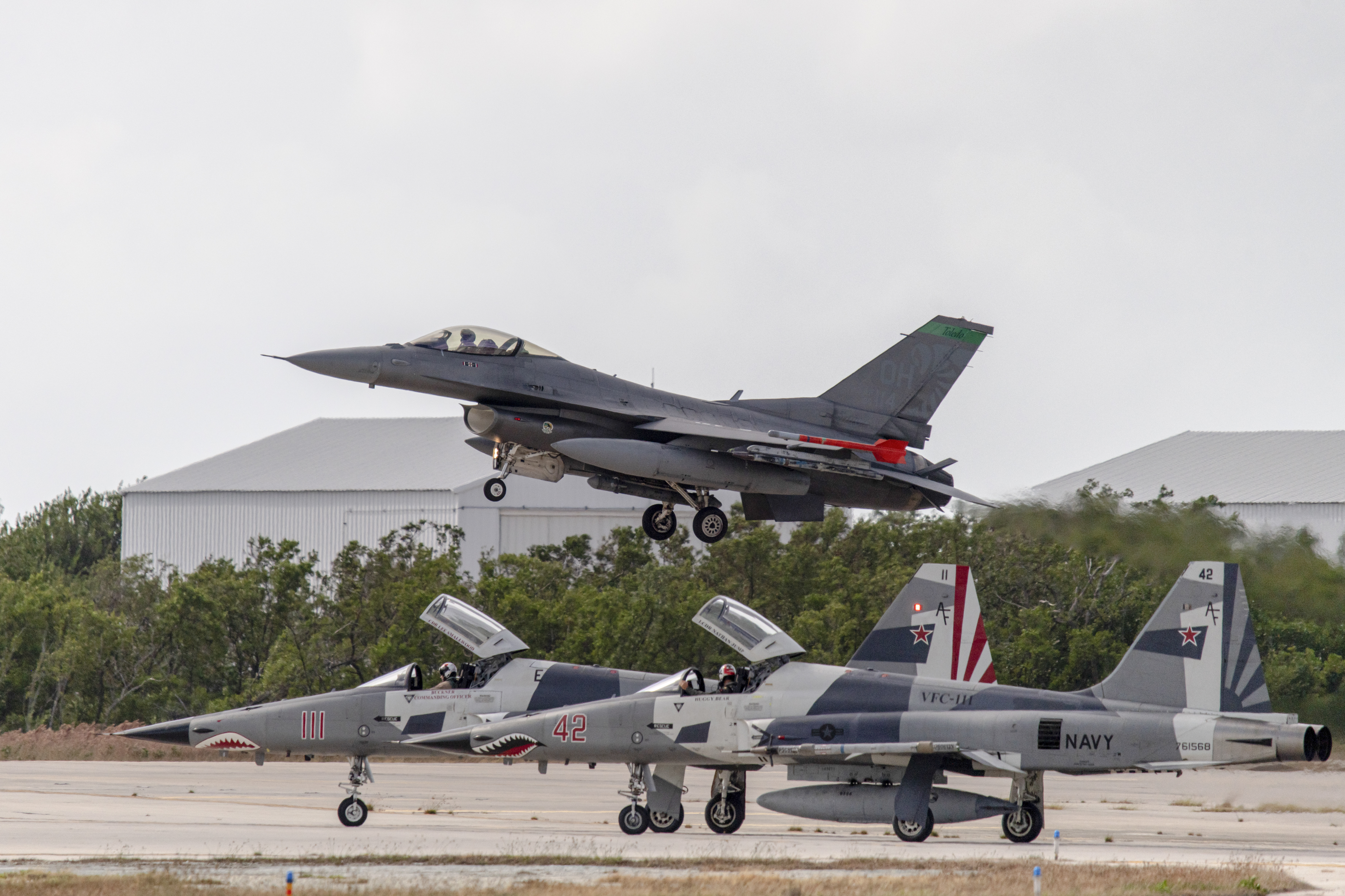 A U.S. Air Force F-16 Fighting Falcon, assigned to the Ohio National Guard's 180th Fighter Wing, lands near U.S. Navy F-5-N Tiger IIs after a training flight at Naval Air Station Key West, Florida, Nov. 2, 2022. The 180FW deployed to Key West to train with VFC-111, the Navy's premier adversary squadron, providing realistic training scenarios that ensure the 180FW is prepared for homeland defense and contingency operations around the globe. (U.S. Air National Guard photo by Staff Sgt. Kregg York) *Some photographic elements have been blurred for security purposes