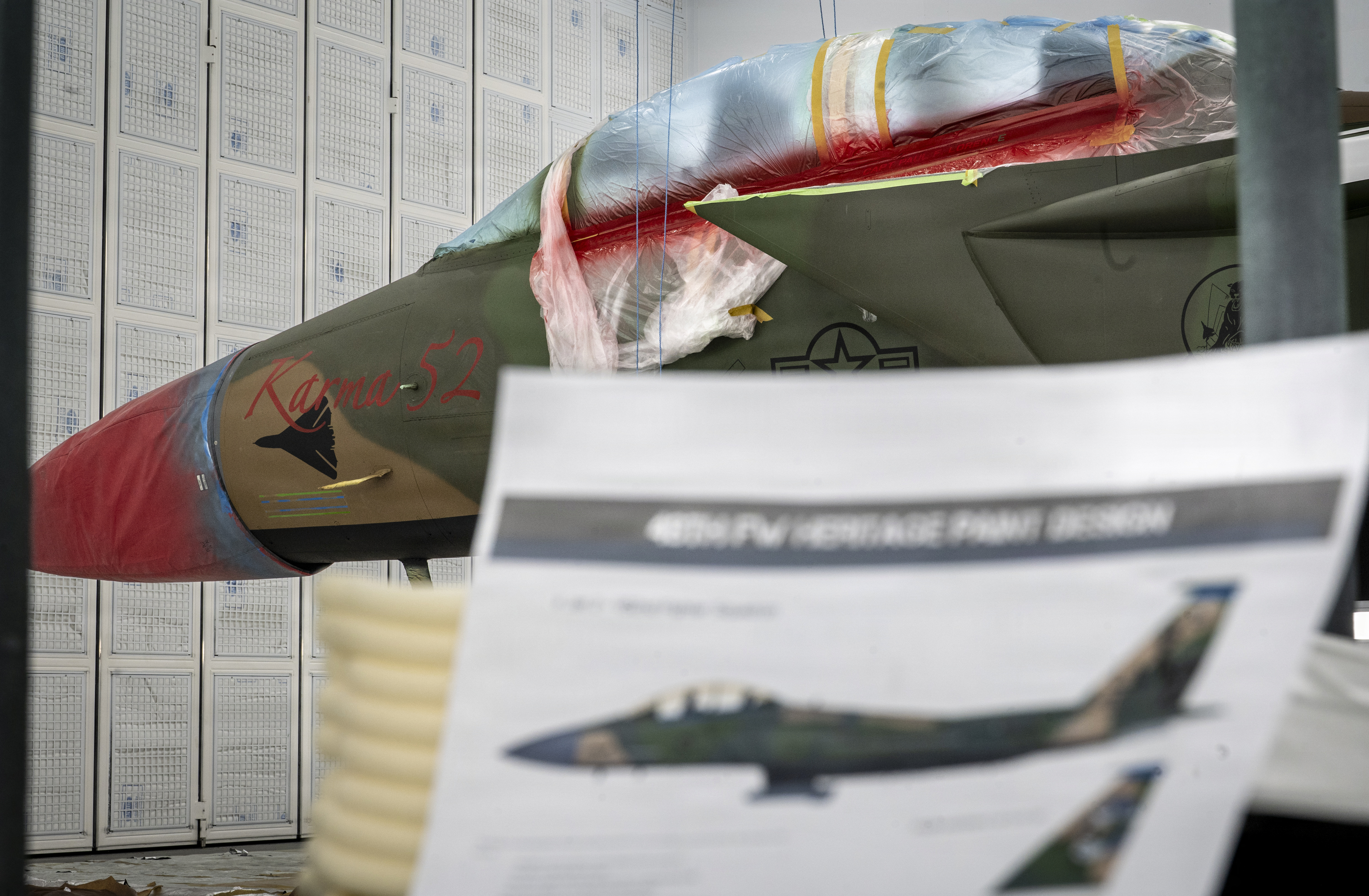 A U.S. Air Force F-15E Strike Eagle aircraft assigned to the 494th Fighter Generation Squadron sits behind a heritage design mock-up at RAF Lakenheath, England, March 18, 2026. During Operation El Dorado Canyon, an F-111F Aardvark “Karma 52” aircraft, the captain and the weapons system officer went missing while flying over the Mediterranean Sea. The markings on the modern paint scheme pay tribute to the personnel and aircraft that were lost during the mission. (U.S. Air Force photo by Airman 1st Class Rilynn Jacobs)