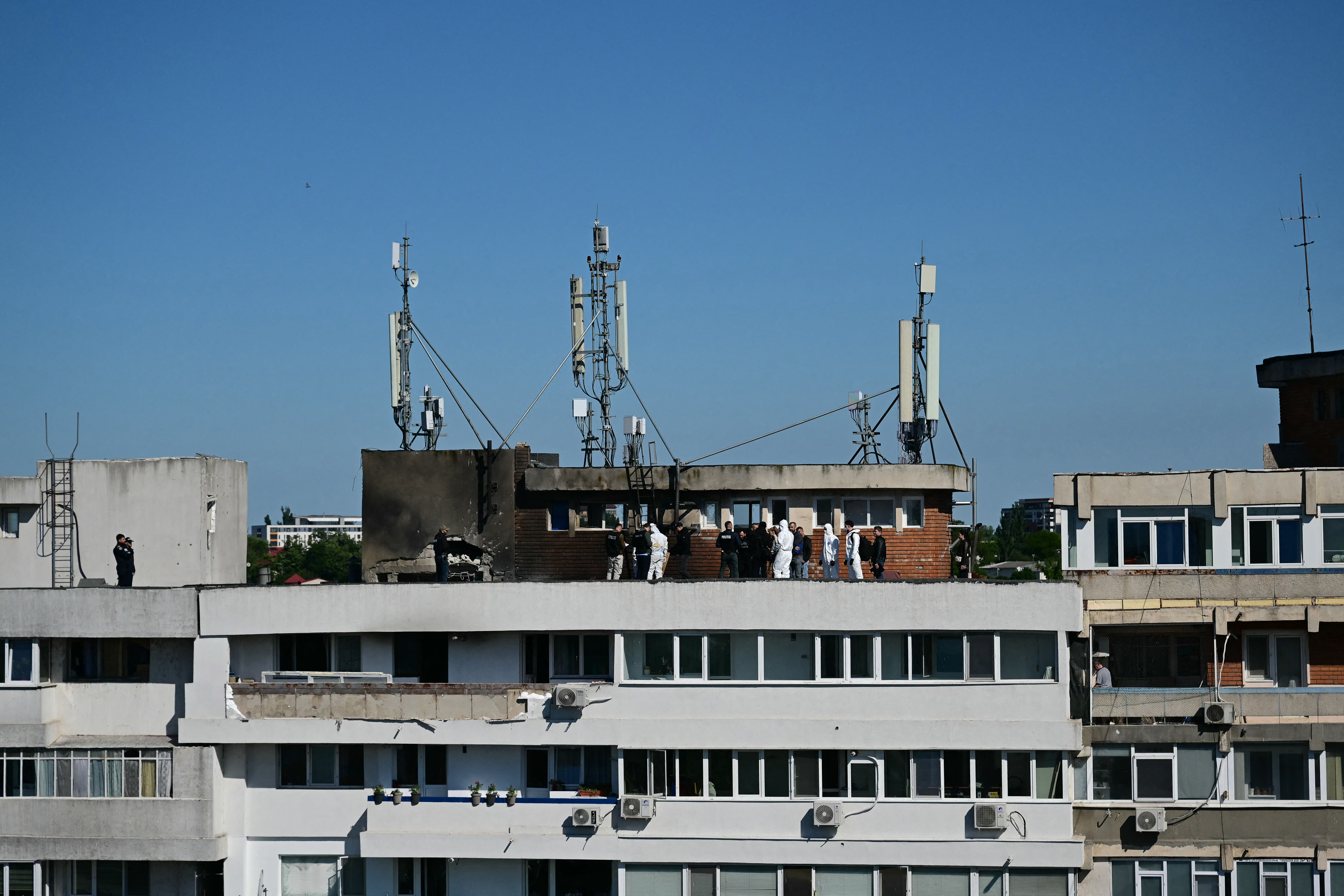 Police and forensic investigators stand on the rooftop as they examine the location of impact (L) over a damaged apartment after a Russian drone struck an apartment building in Galati, eastern Romania. A Russian drone wounded two people as it struck an apartment building in NATO-member Romania, its defence ministry said on May 29, 2026, the latest spillover from the four-year war into neighbouring states. (Photo by Daniel MIHAILESCU / AFP via Getty Images)
