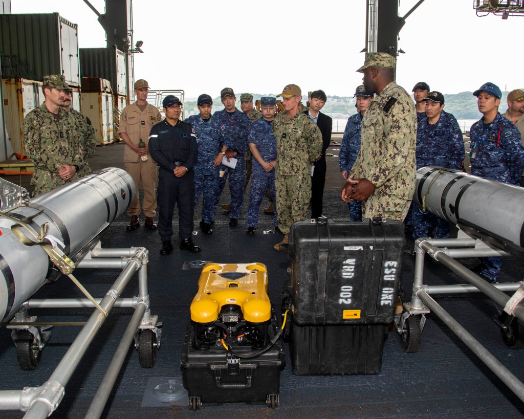 SASEBO, Japan (May 15, 2025) – A Sailor assigned to Explosive Ordnance Disposal Mobile Unit 5, describes the capabilities of the MK 18 Mod 2 Kingfish unmanned underwater vehicle and a remotely operated vehicle (ROV) to Japan Maritime Self-Defense Force Rear Adm. Yatsutaka Ebata, commander, Escort Flotilla 2, and Rear Adm. Tom Shultz, commander, Task Force (CTF) 76, during the Integrated Battle Problem 25.5 technology demonstration aboard the Lewis B. Puller-class Expeditionary Sea Base USS Miguel Keith (ESB 5), at Fleet Activities Sasebo, Japan, May 15, 2025. Exercises such as Integrated Battle Problem allow the Navy to demonstrate unmanned system operations in relevant experiment scenarios in order to meet service level objectives and operationalize unmanned systems and capabilities to maintain a secure and prosperous Indo-Pacific region. U.S. 7th Fleet, the U.S. Navy’s largest forward-deployed numbered fleet, routinely interacts and operates with allies and partners in preserving a free and open Indo-Pacific region. (U.S. Navy photo by Mass Communication Specialist 1st Class W. Chase Stephens)