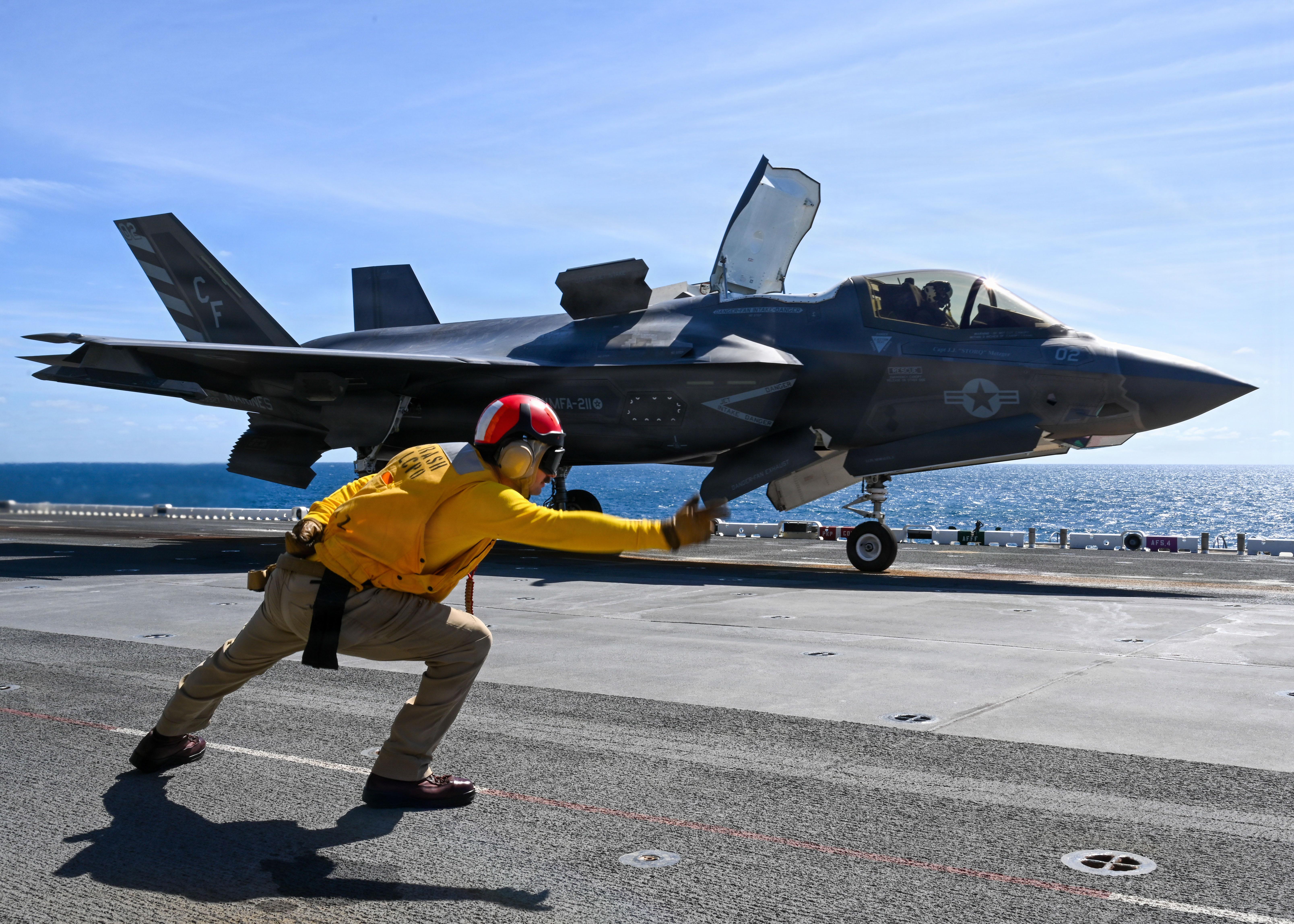 Chief Aviation Boatswain’s Mate (Handling) Derek Kropfl, assigned to the Wasp-class Amphibious assault ship USS Essex (LHD 2), directs an F-35B Lighting II attached to Marine Fighter Attack Squadron (VMFA) 211 to take off during flight deck operations April 22, 2026. Essex is currently underway conducting routine operations. (U.S. Navy photo by Mass Communication Specialist Seaman Ivan A. Garcia)